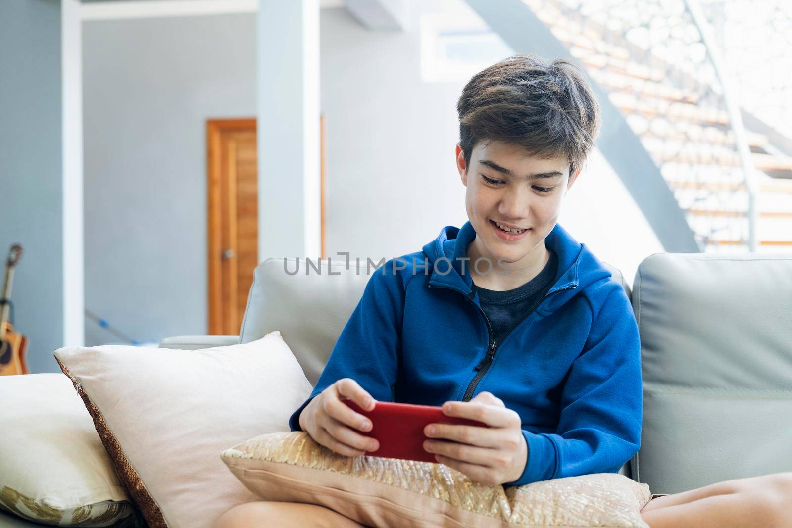 The boy playing online game on smartphone at home.