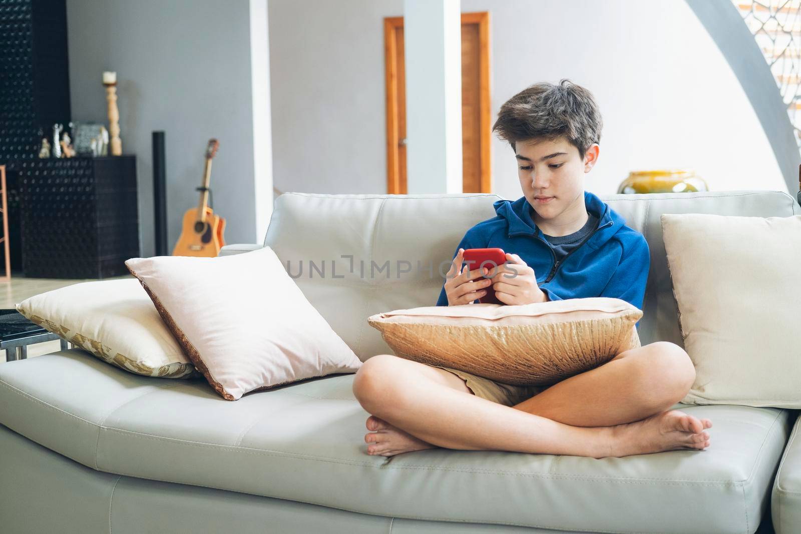 The boy playing online game on smartphone at home.