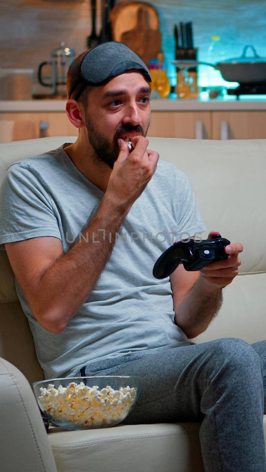 Upset pro gamer sitting on couch and playing soccer videogames by DCStudio