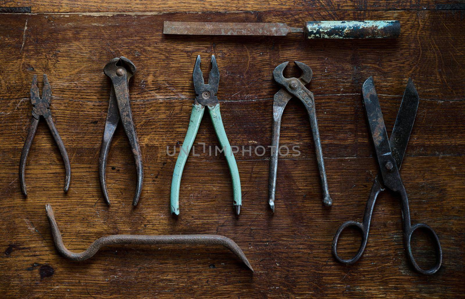 old and rusty tools on an antique lacquered wood table by ISRAFOTO