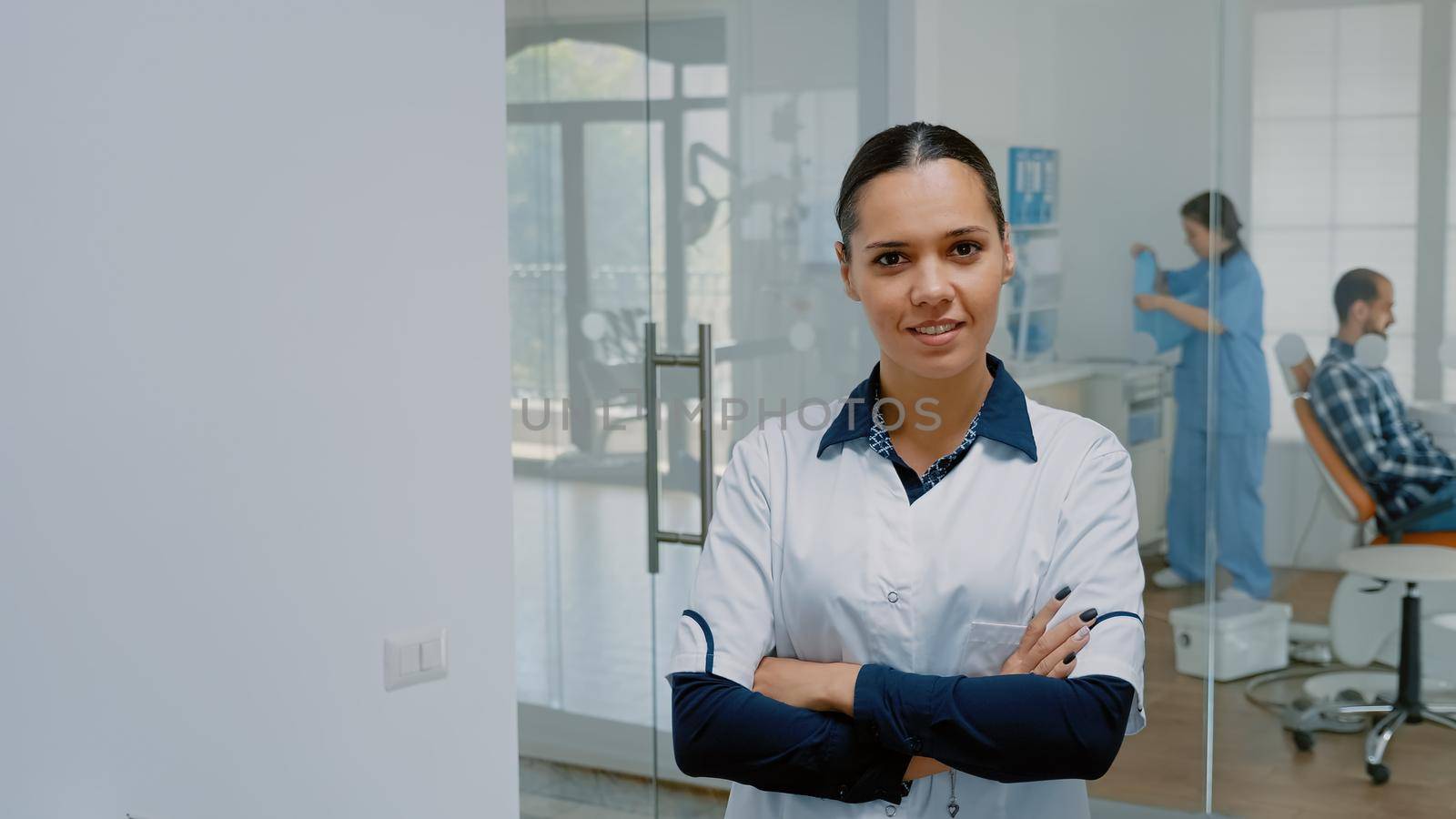 Portrait of caucasian stomatologist in uniform smiling and looking at camera in dental office space. Woman with dentistry expertise and dentist profession standing at oral care clinic