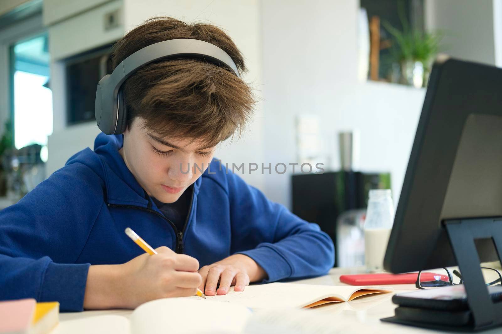 Distance learning online education. A schoolboy boy studies at home and does school homework. A home distance learning.