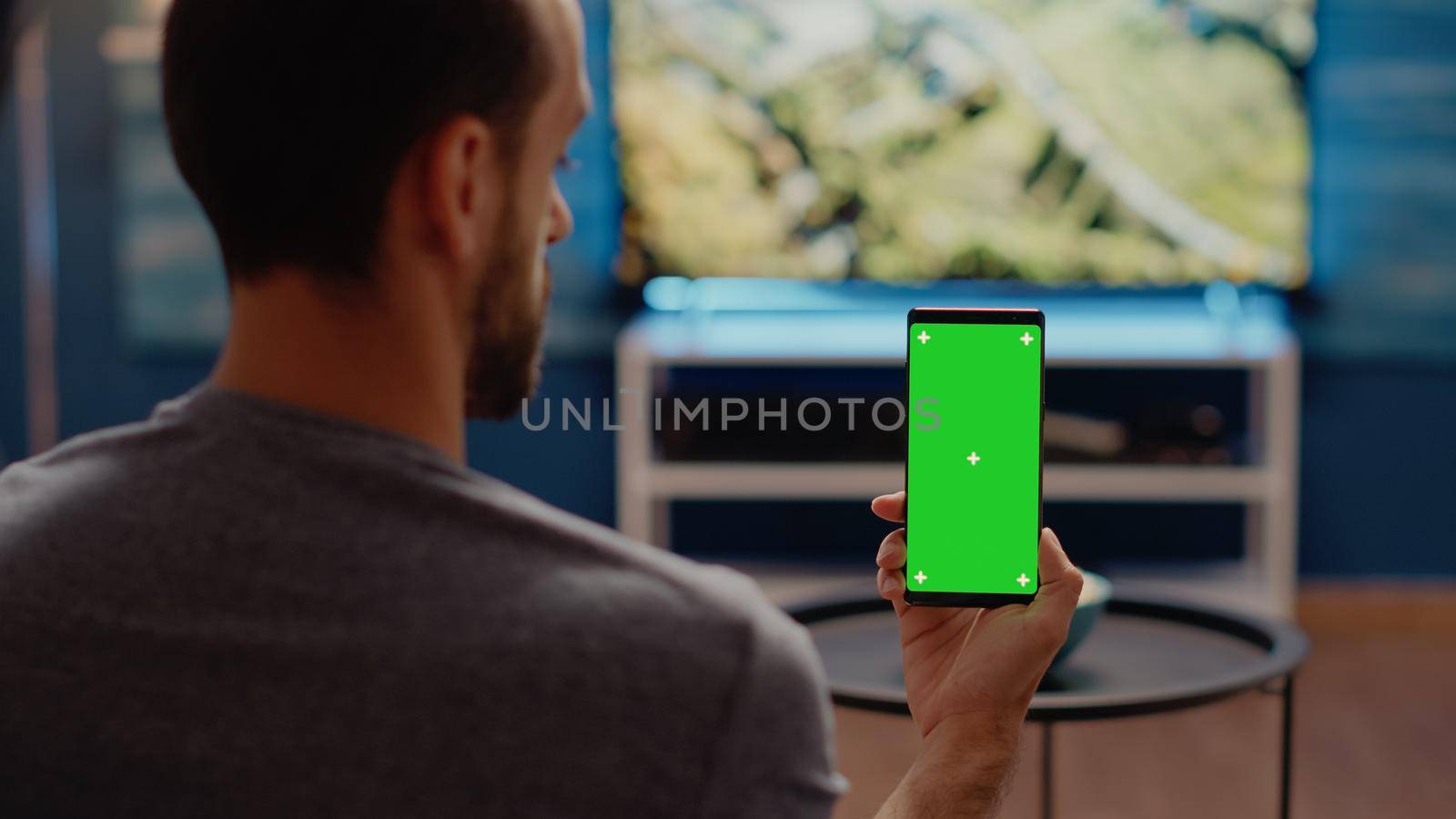 Person with modern smartphone looking at green screen by DCStudio