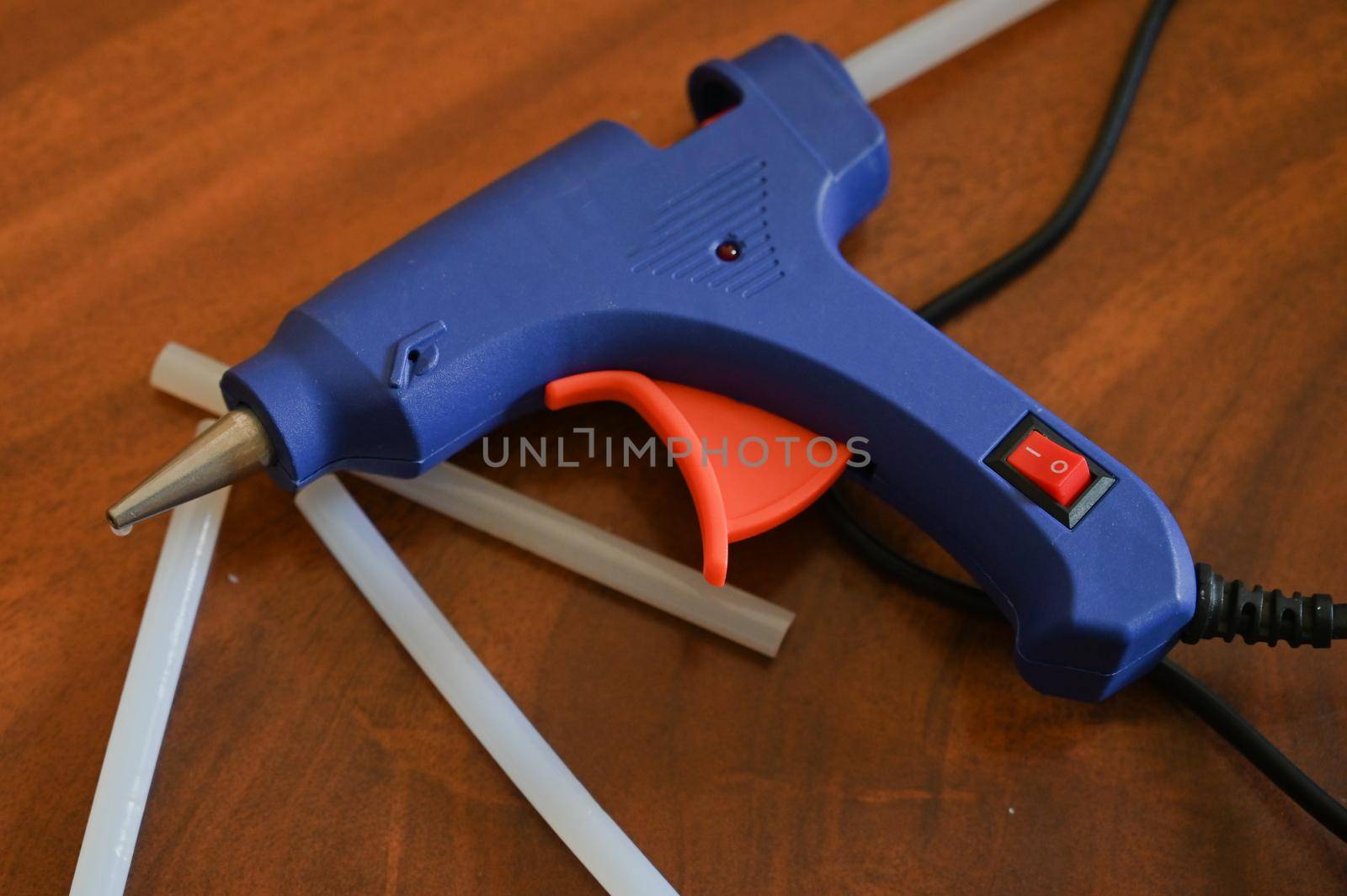 a glue gun with glue rods is lying on the table close-up