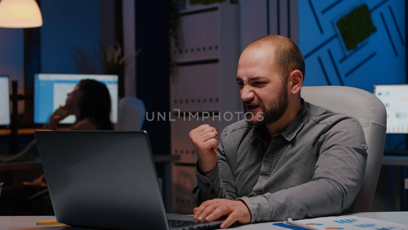 Happy cheerful businessman working in startup company office late at night enjoying online job promotion. Smart executive manager analyzing executive business corporate project