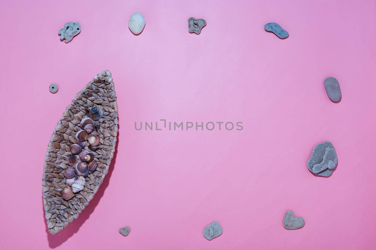 wicker plate in the form of a canoe with shells pink background by ISRAFOTO