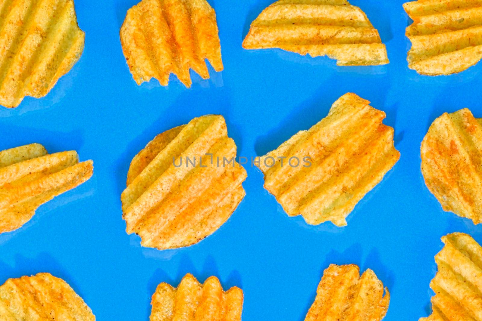 Ribbed potatoes snack with pepper on blue background. Ridged potato chips on blue background. Collection. Flat lay. Close-up.