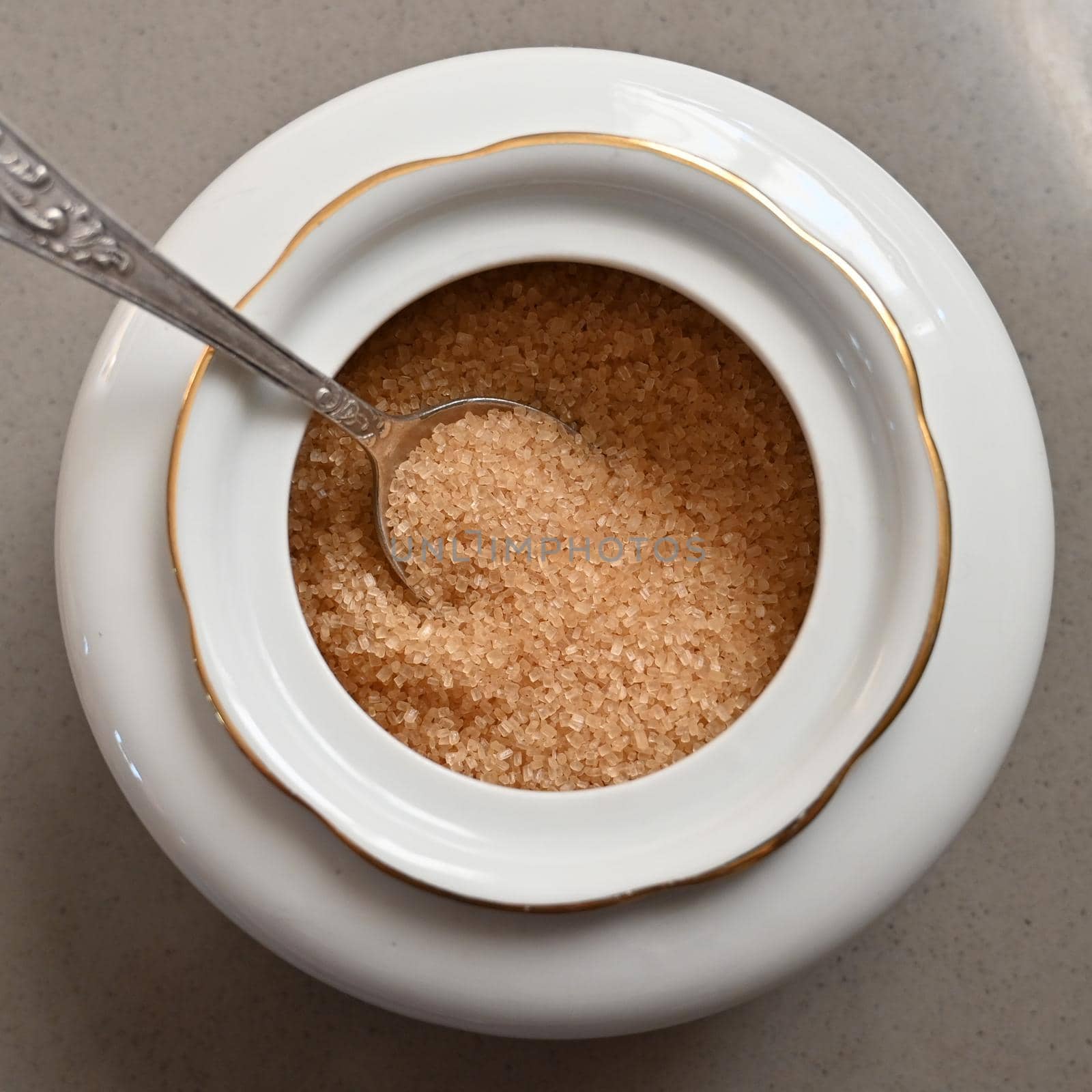 Cane sugar in a porcelain sugar bowl with a spoon close-up