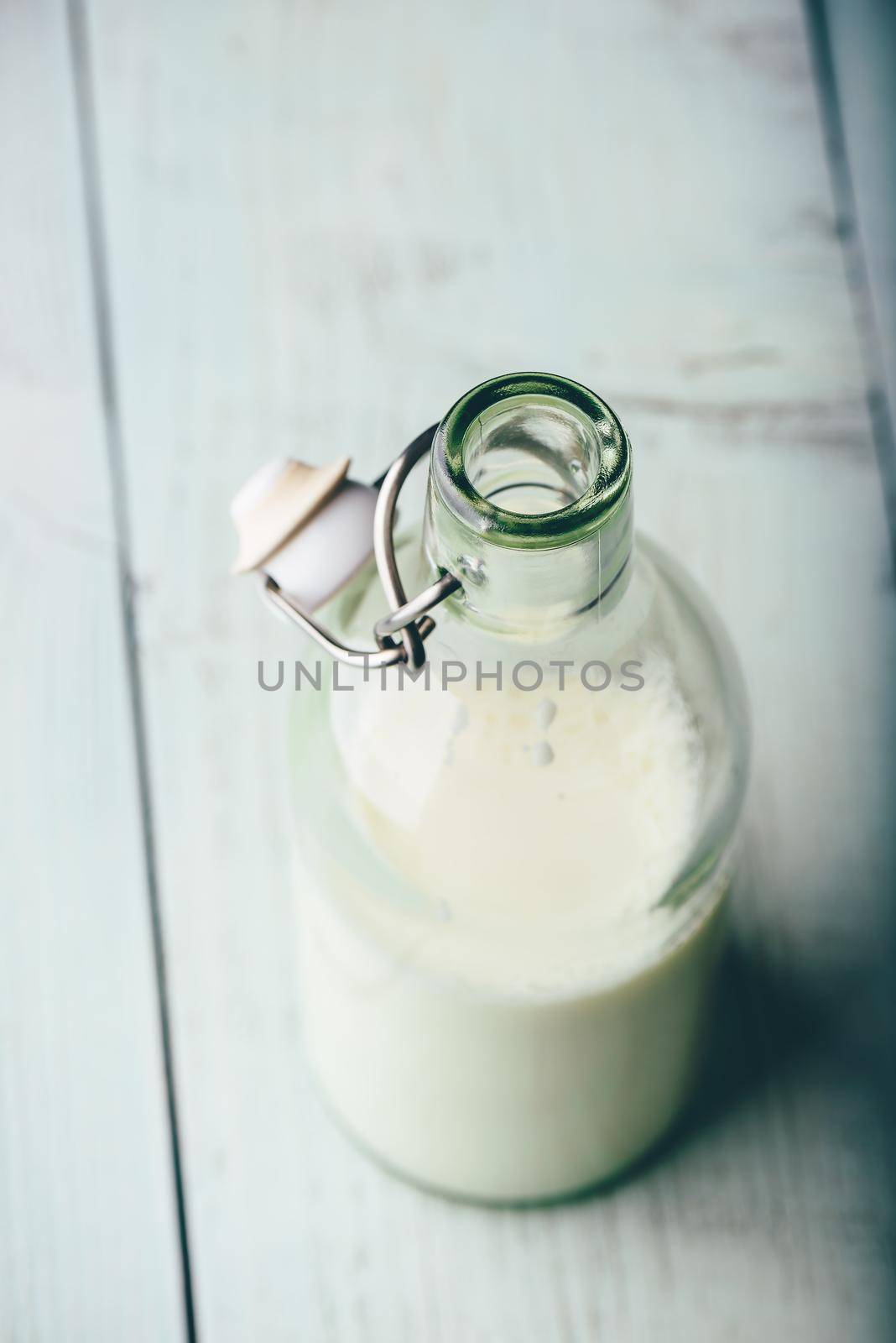 Milk in glass bottle on wooden surface. High angle view