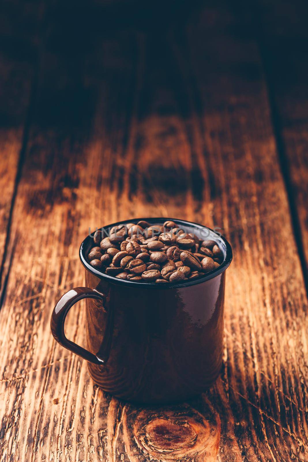 Metal mug full of roasted coffee beans