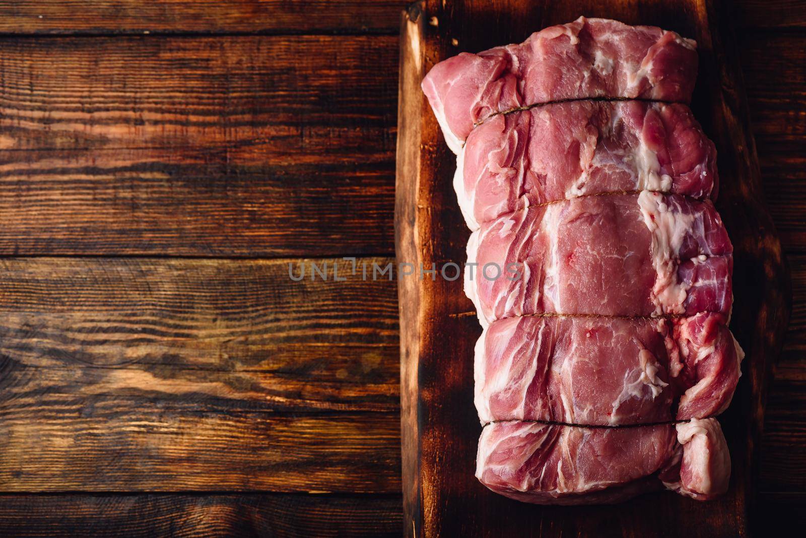 Pork loin joint on rustic cutting board. View from above