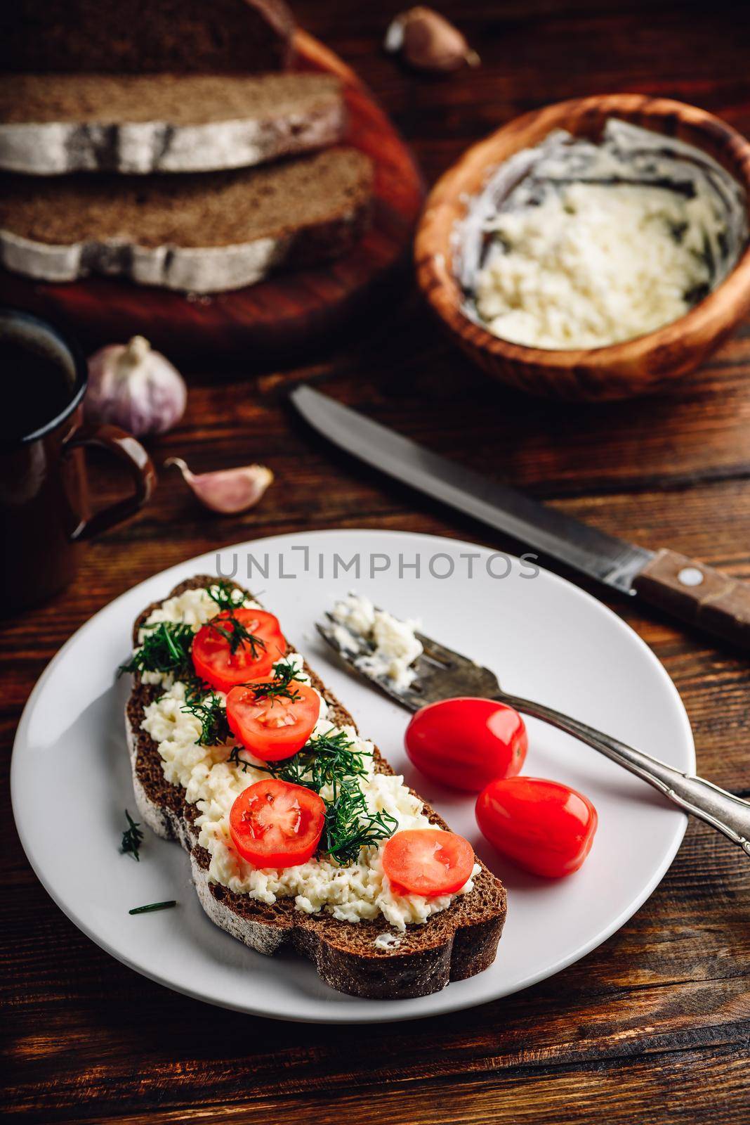 Rye bread toast with processed cheese, garlic and sliced cherry tomatoes