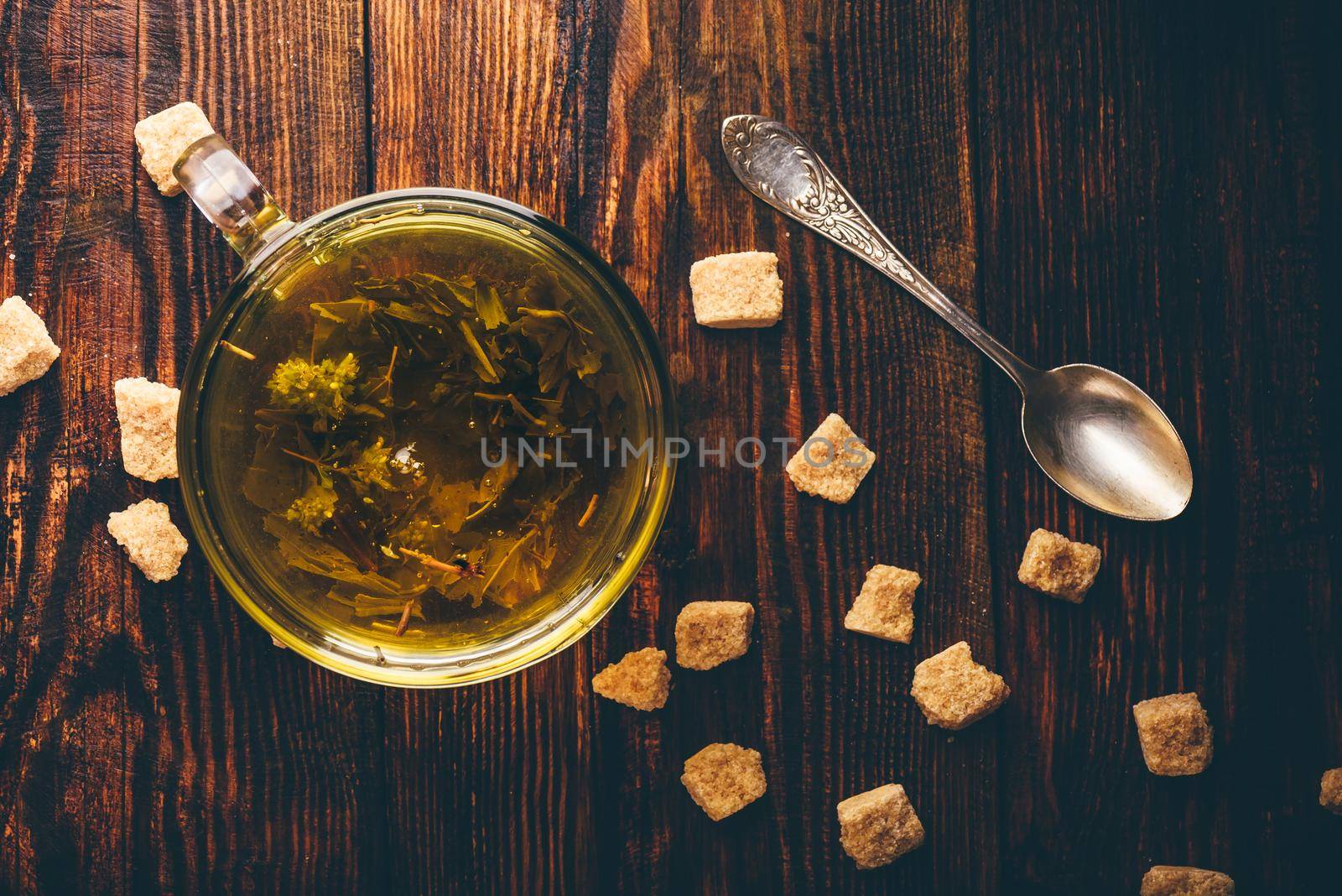 Tea with brown tea sugar on a wooden background