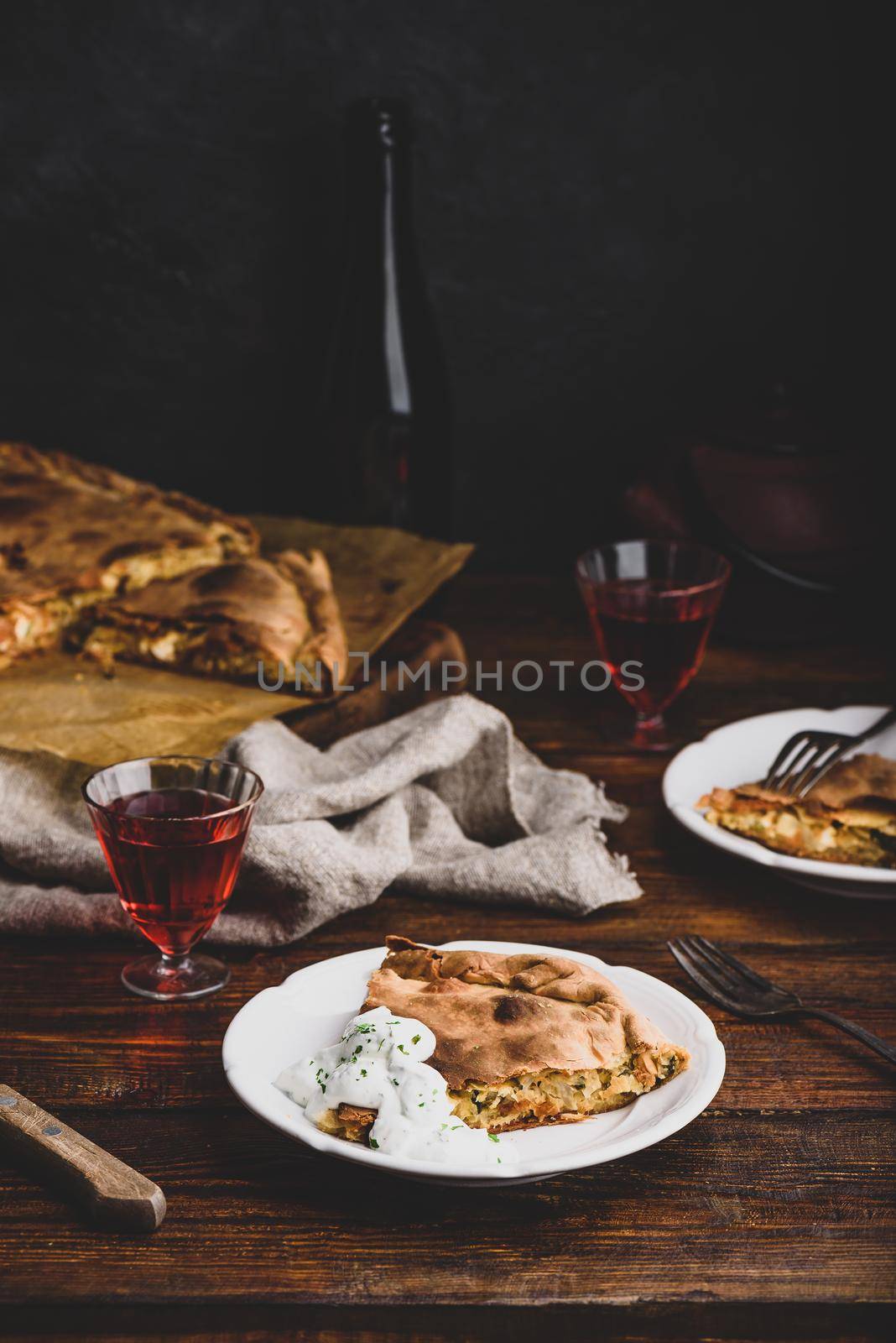 Slice of cabbage pie with sour cream sauce on white plate