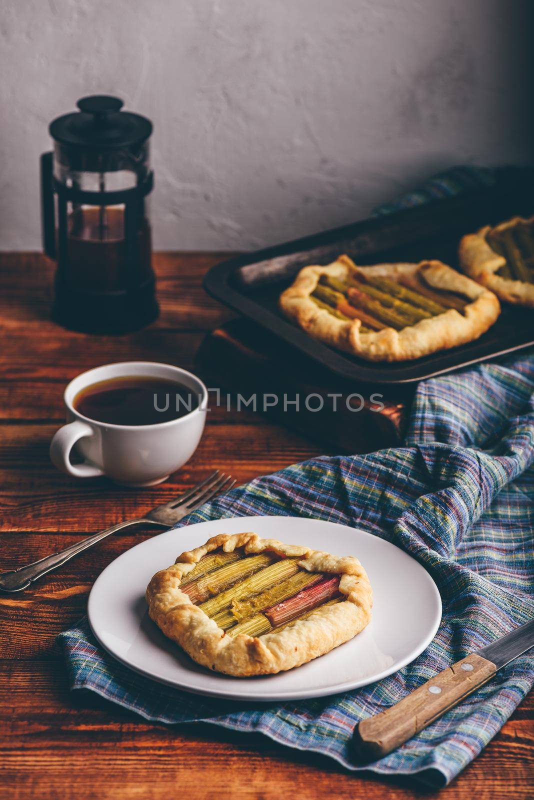 Rhubarb mini galette on white plate and cup of coffee