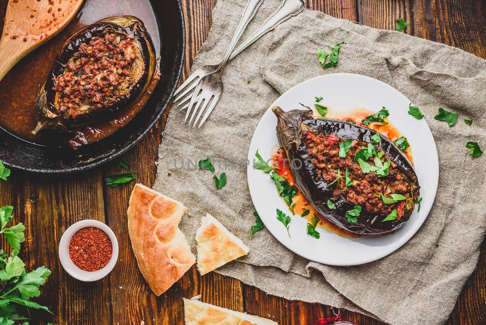 Baked eggplant stuffed with ground beef, tomatoes and spices on white plate. Traditional dish Karniyarik of turkish cuisine. View from above