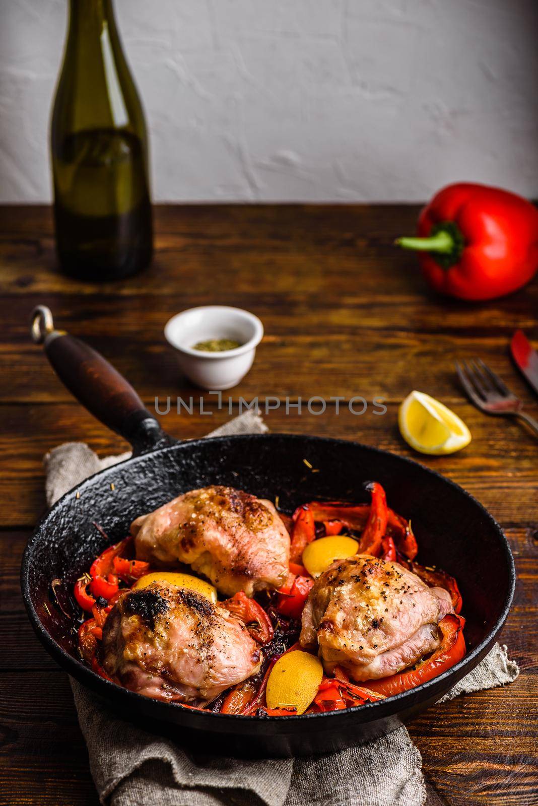 Chicken thighs baked with red bell peppers, rosemary and lemon in cast iron skillet.