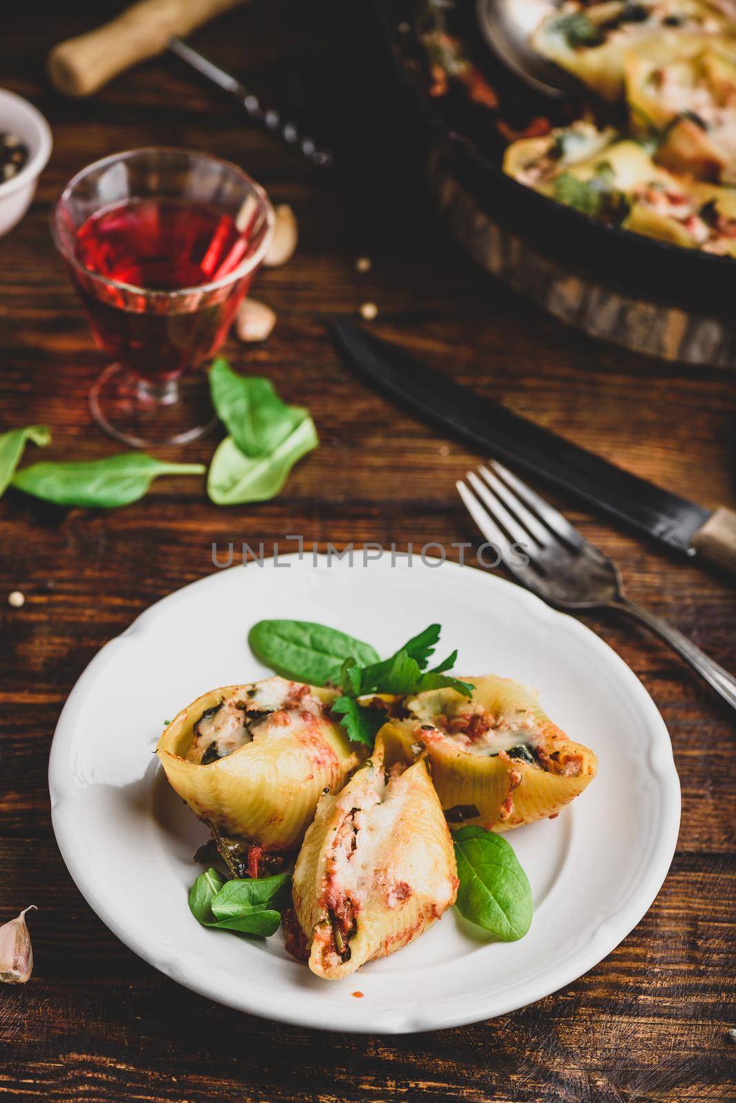 Baked jumbo shells pasta stuffed with ground beef, spinach and cheese on white plate