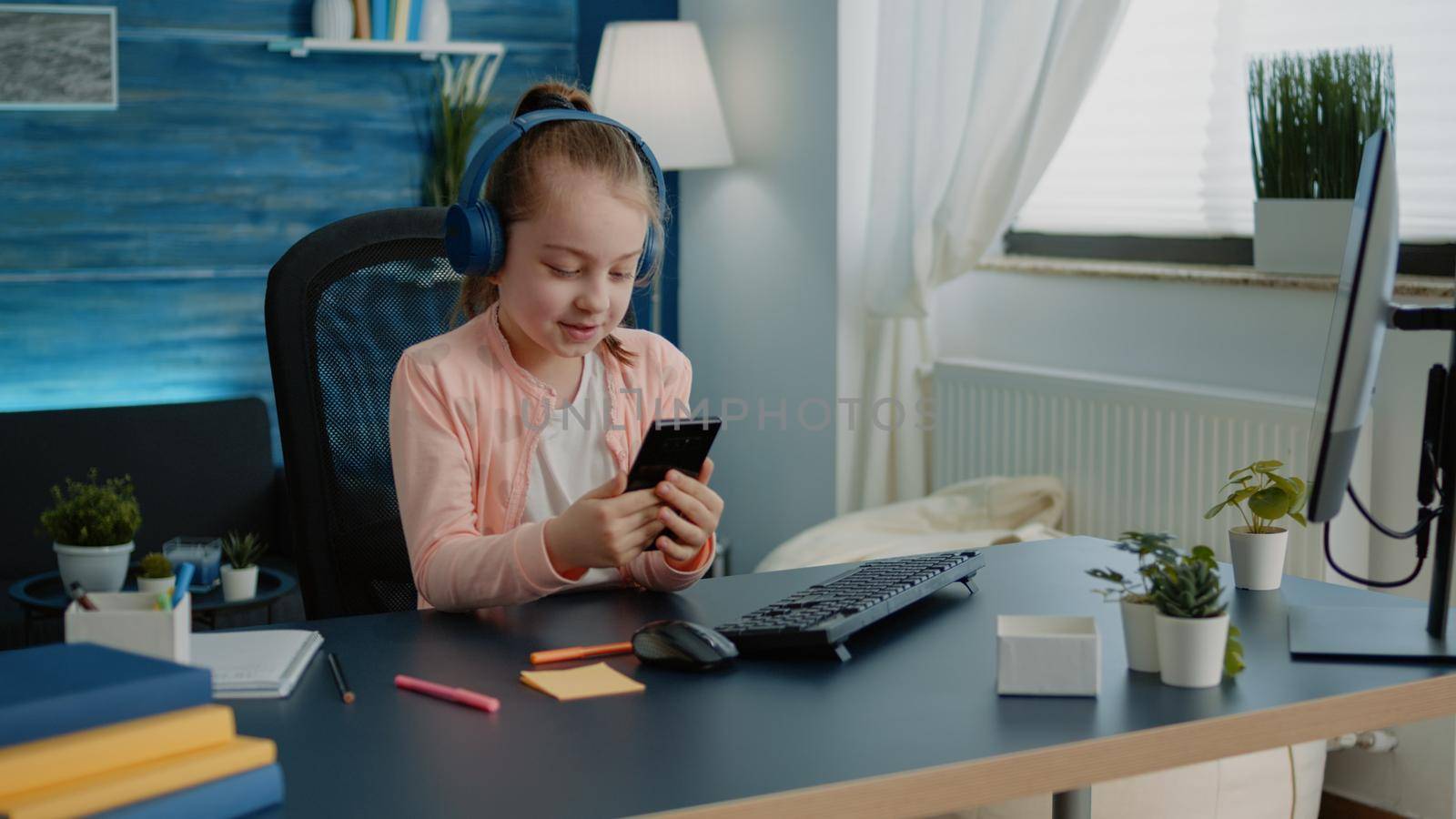 Little girl using smartphone for lessons on video call at desk. Young child talking on online conference for remote school work with teacher on internet classes. Pupil with modern device