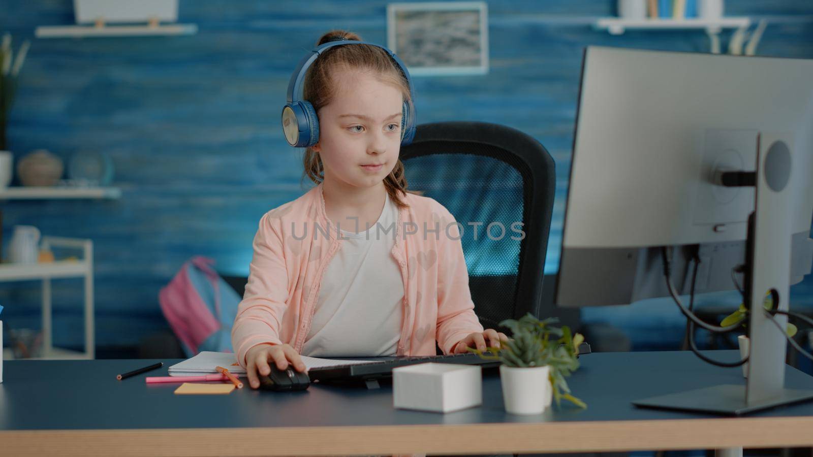 Young child wearing headphones and drawing on textbook by DCStudio