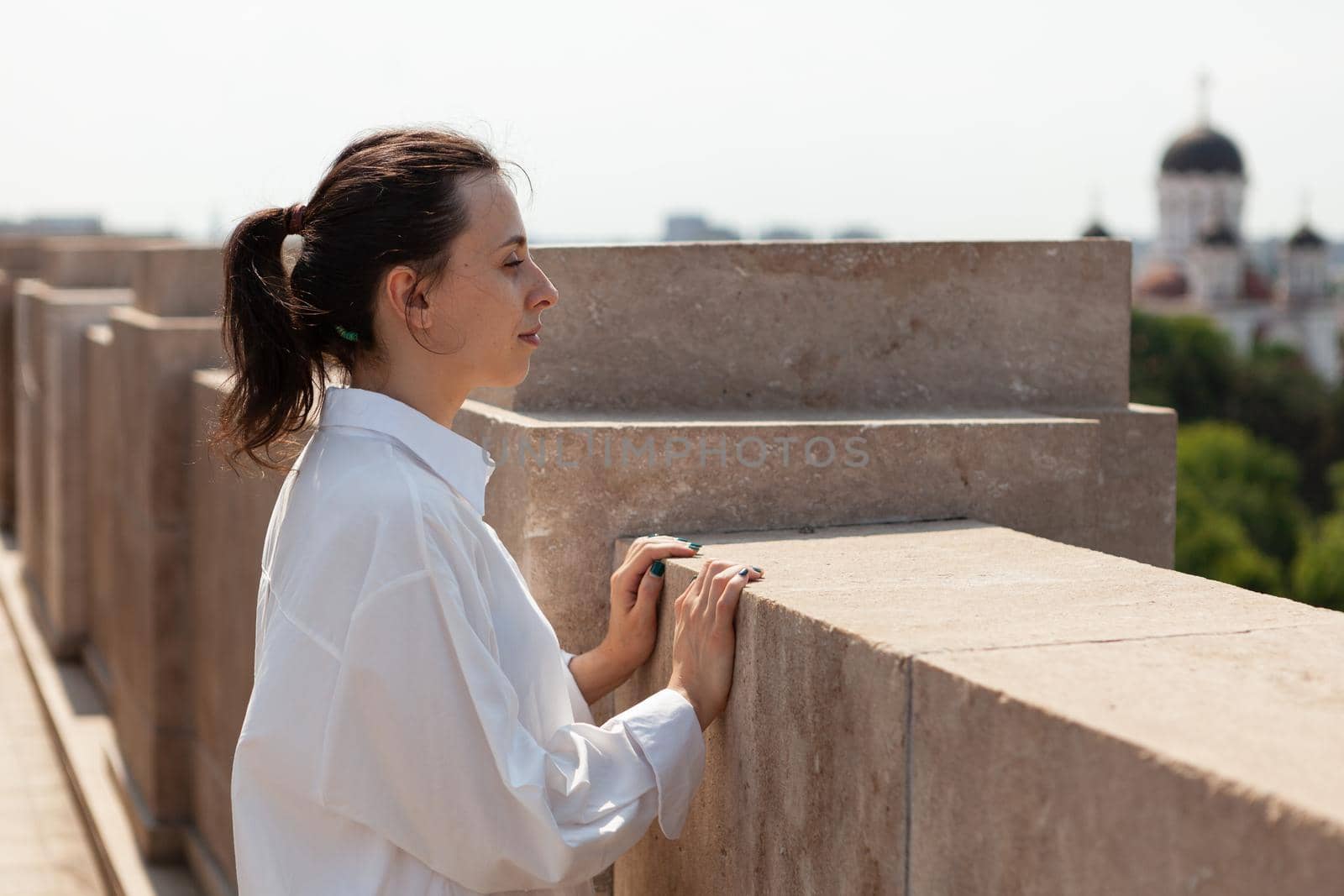 Toursit woman looking at metropolitan city from panoramic terrace of bulding tower enjoying summer vacation. View of city skyline from observation point. Panoramic view of buildings