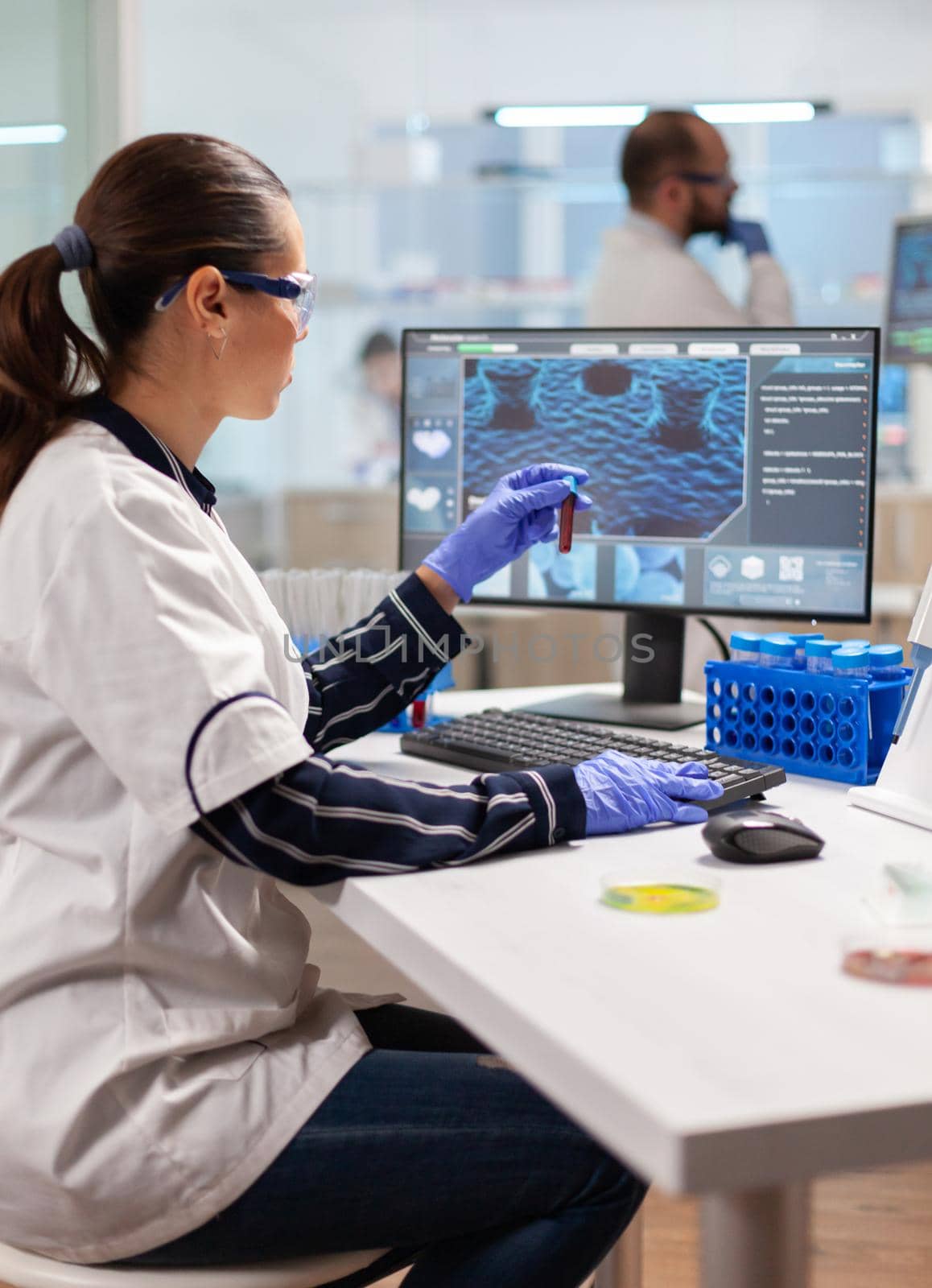 Pharmaceutical chemist looking at test tube with blood for vaccine experiment. Healthcare scientist working in modern laboratory using modern technology.