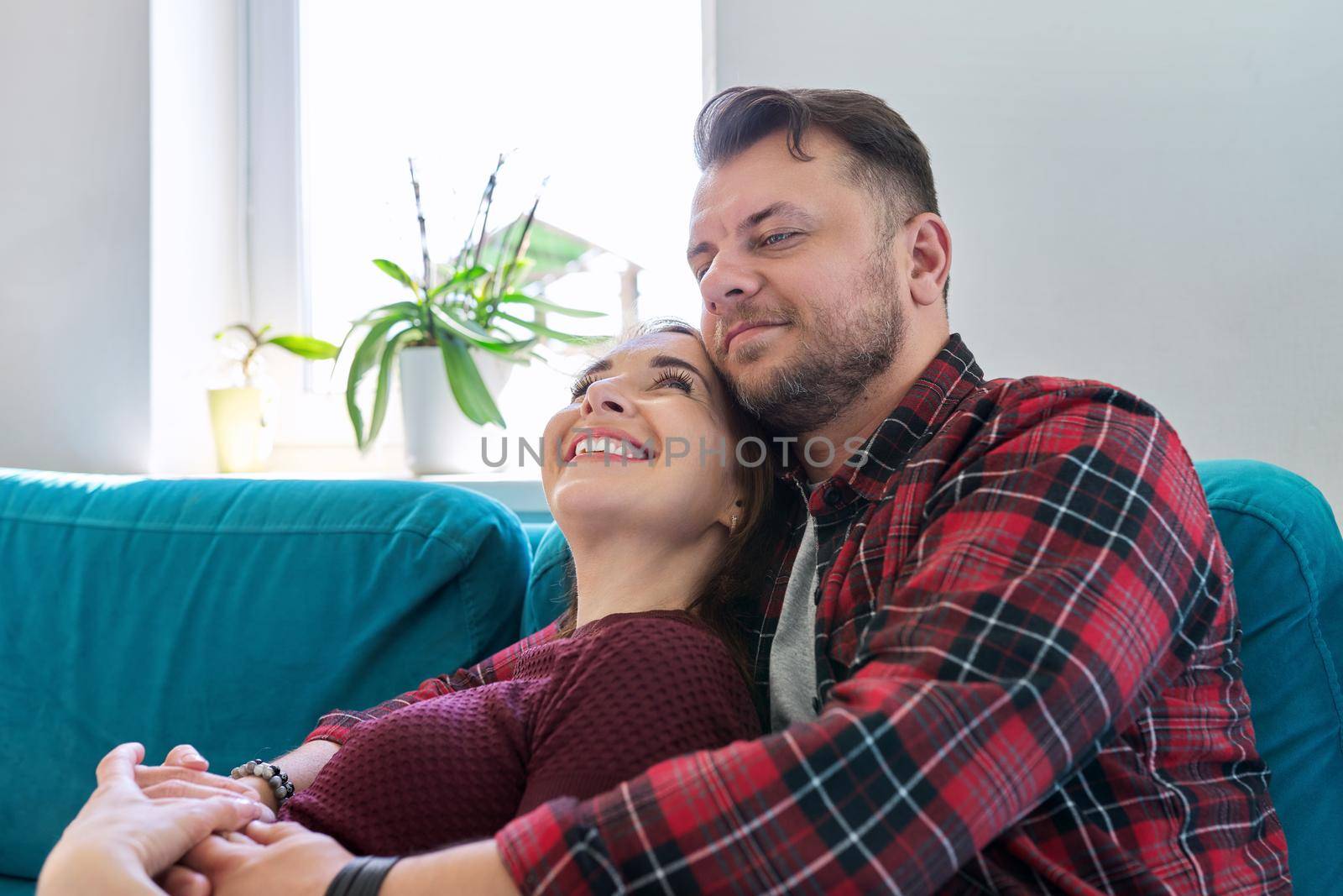 Happy middle-aged couple embracing at home on the couch. Family, happiness, love, relationships, people 40 years old concept