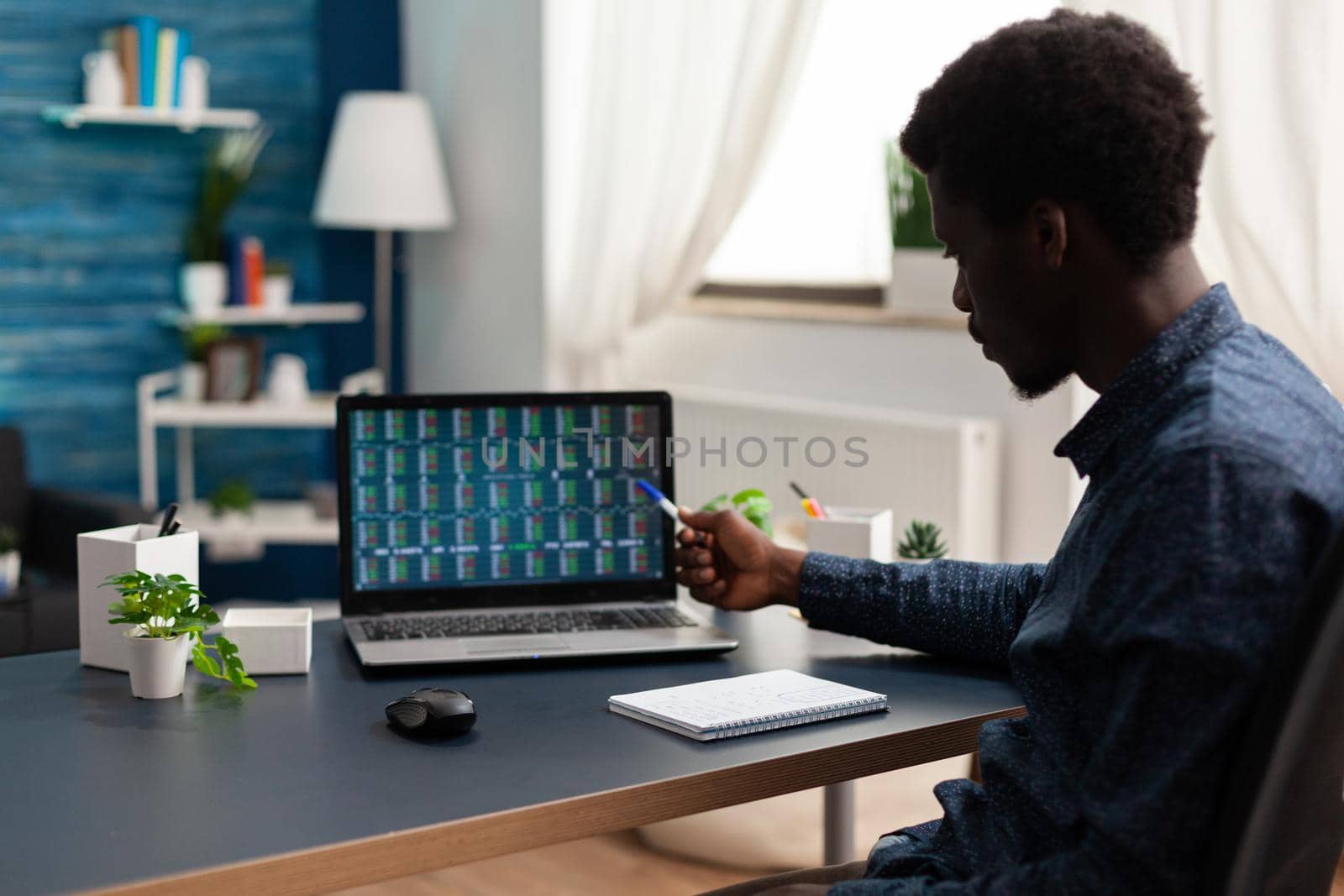 African american businessman doing market analysis working at cryptocurrency report analyzing blockchain chartsusing laptop in living room. Stock market exchange trading crypto currency on screen