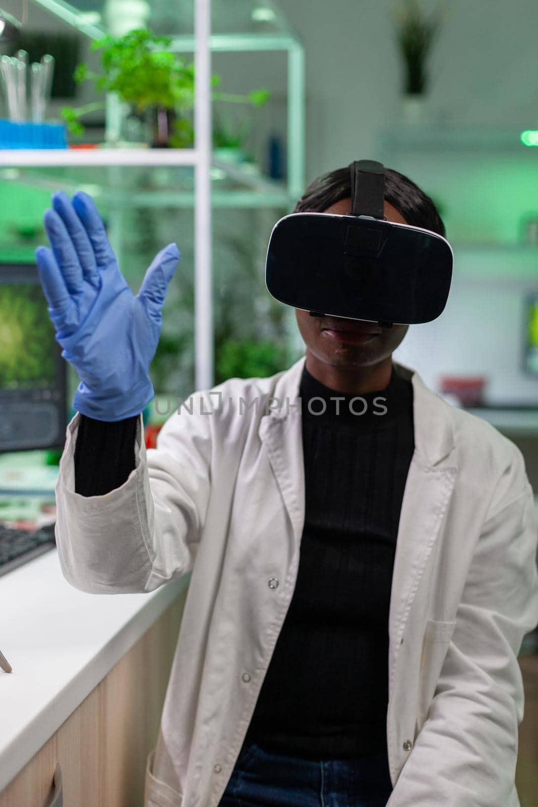 African scientist biologist conducting research using virtual reality wearing vr headset. Medical team working in pharmaceutical laboratory analyzing dna test.