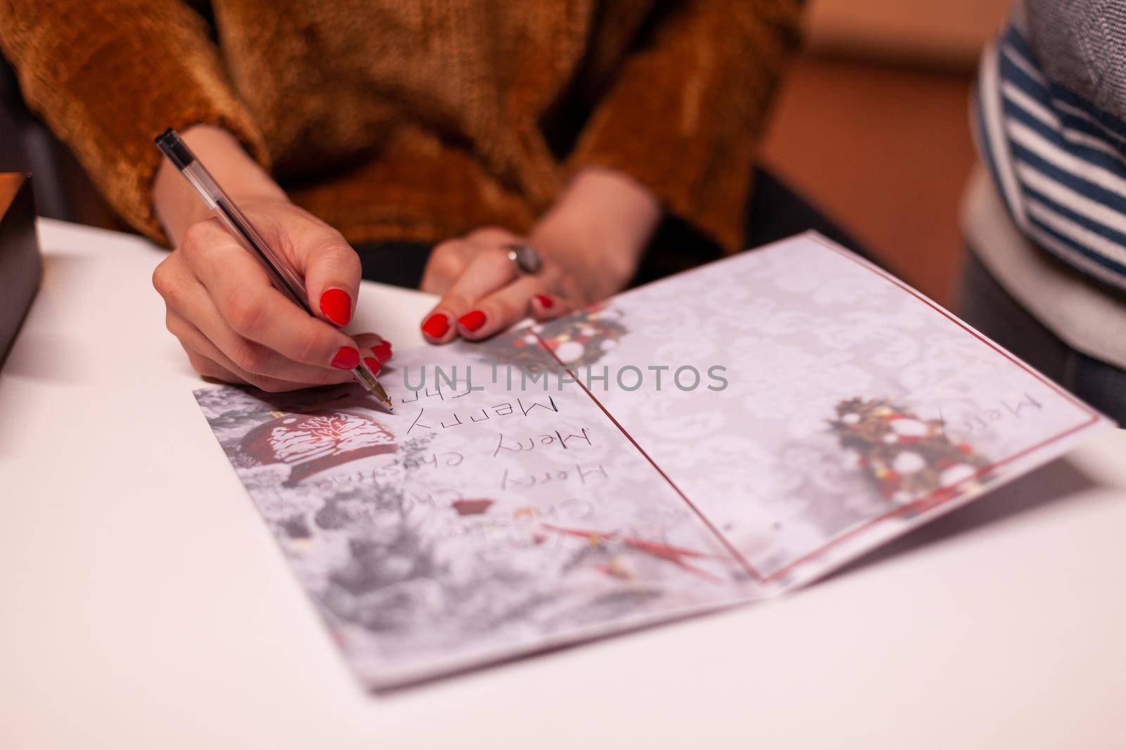 Closeup of woman hands writing xmas greeting card for family during christmas holiday by DCStudio