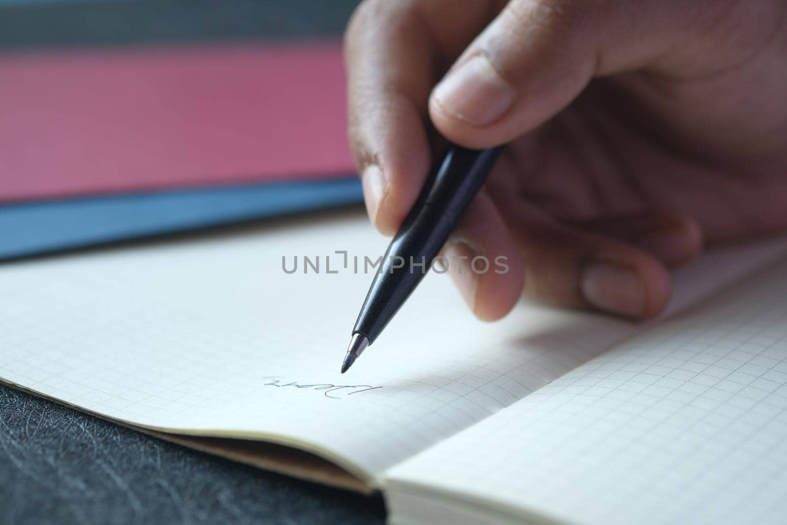 man hand writing on notepad while sited ,