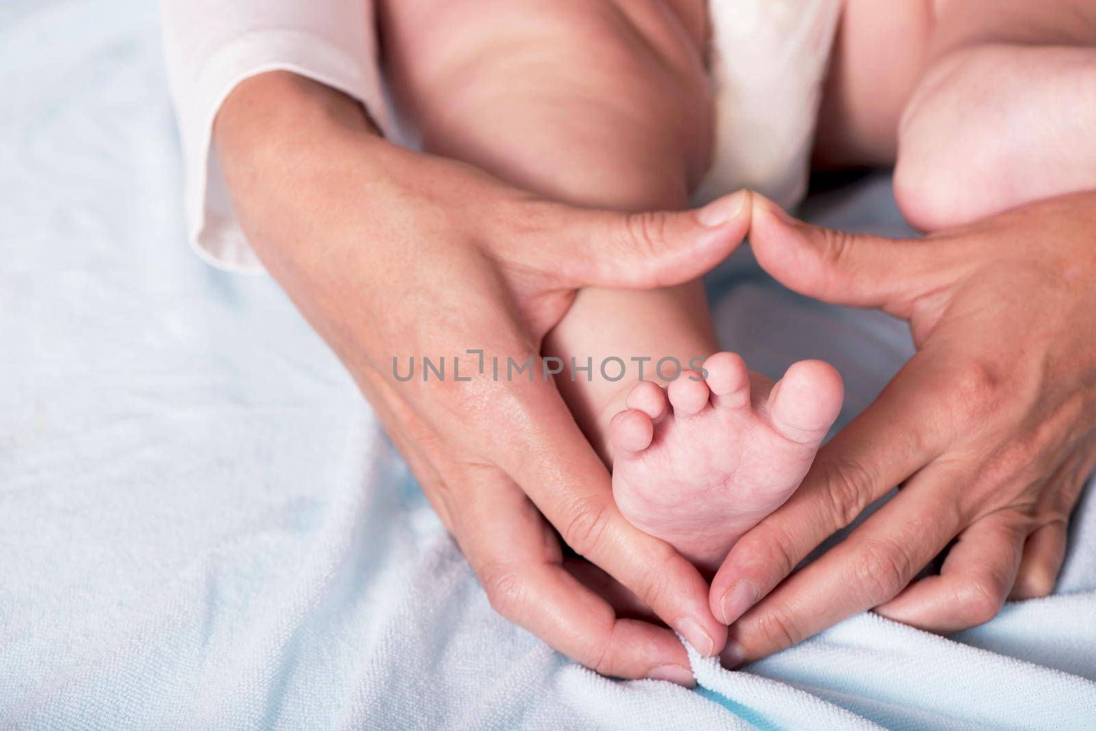 Children's feet in heart-shaped hands of mother. Beautiful conceptual image of Motherhood