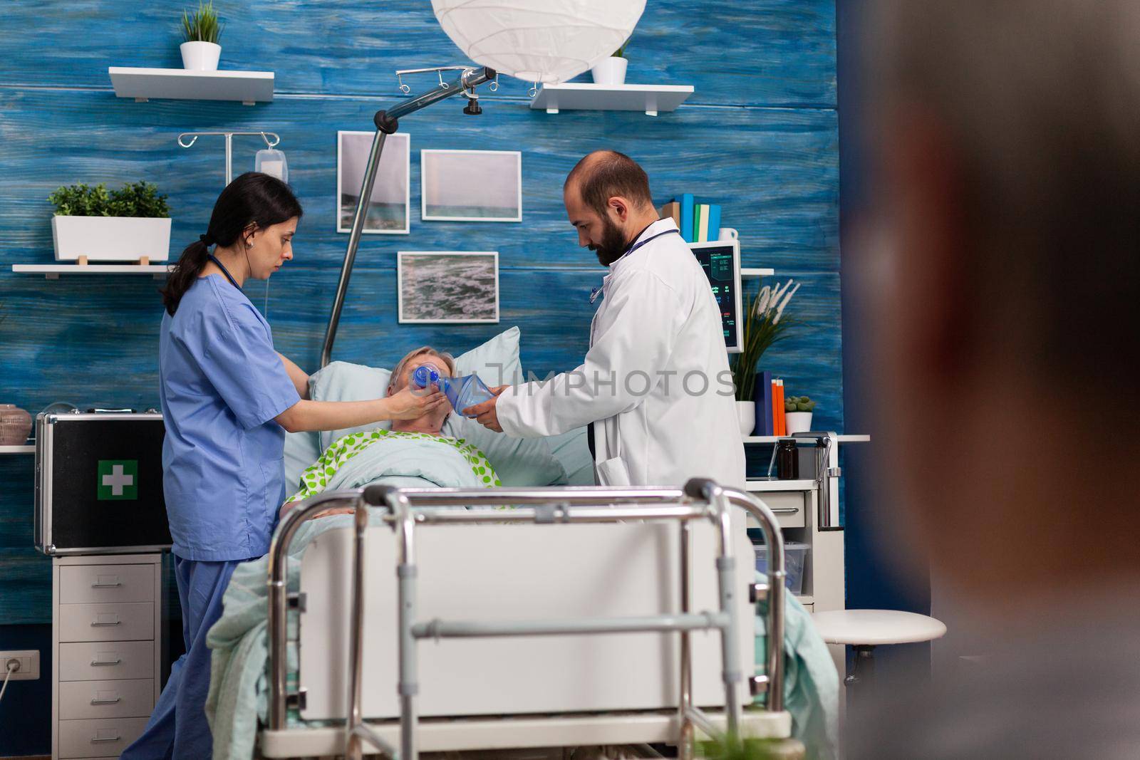 Social support asisstants helping sick hospitalized senior woman breath, with ambu bag during resustacitor process. Social services nursing elderly retired female. Healthcare assistance