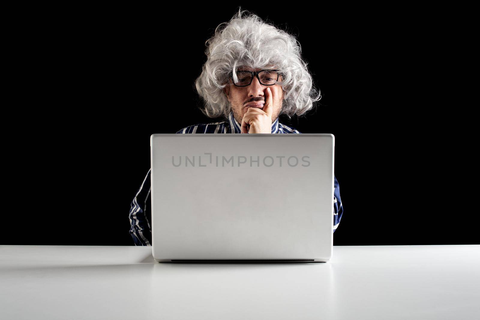 An elder serious man lost in thoughts in front of a laptop computer, focused boomer or absent-minded thinking of problem solution, worried puzzled senior pondering question at work