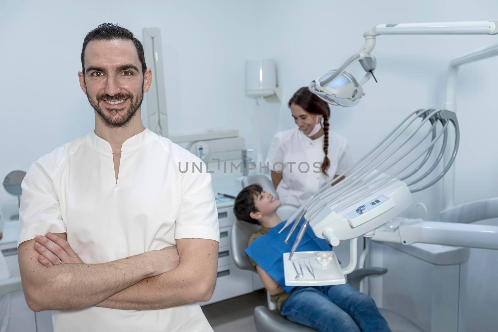 A portrait of a dentist with his team working in the background by Antonelli