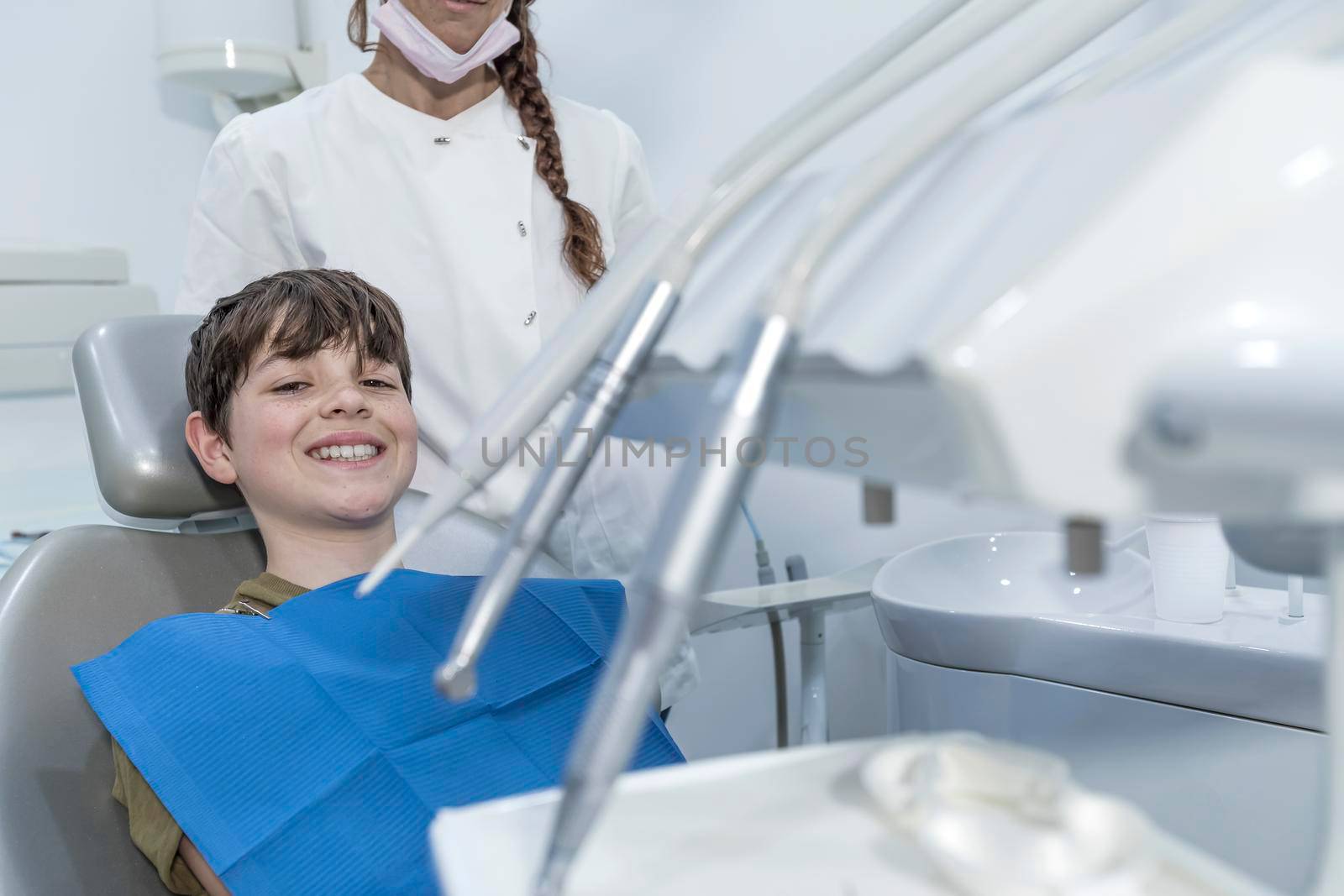 A cute boy is being examined by a professional pediatric dentist. Very happy boy after the visiting of doctor at the clinic with beautiful white smiles. Copy space.