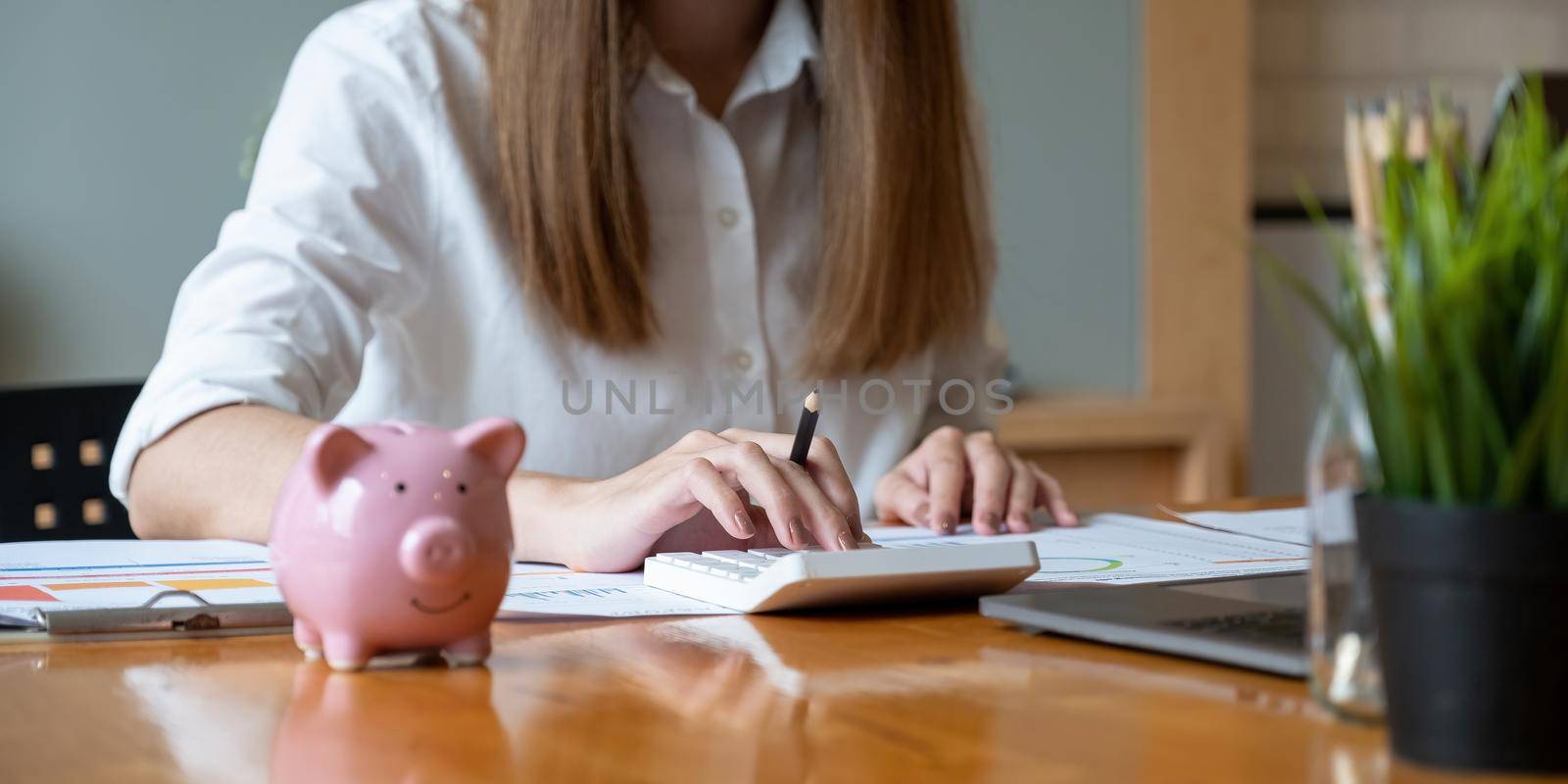 Business woman using calculator with computer laptop, budget and loan paper in office. Business accounting concept by nateemee