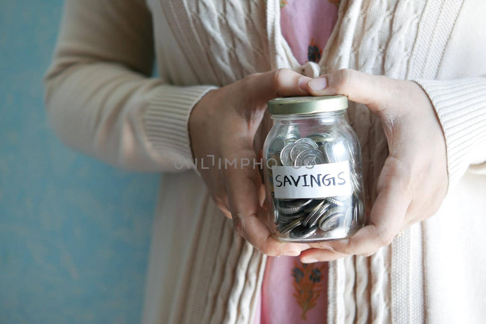 women hand hold a saving coins jar .