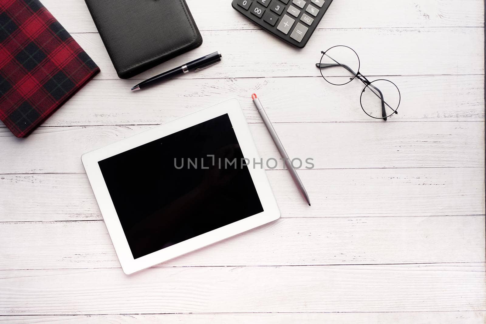 Flat composition of digital tablet and office stationary on black background .