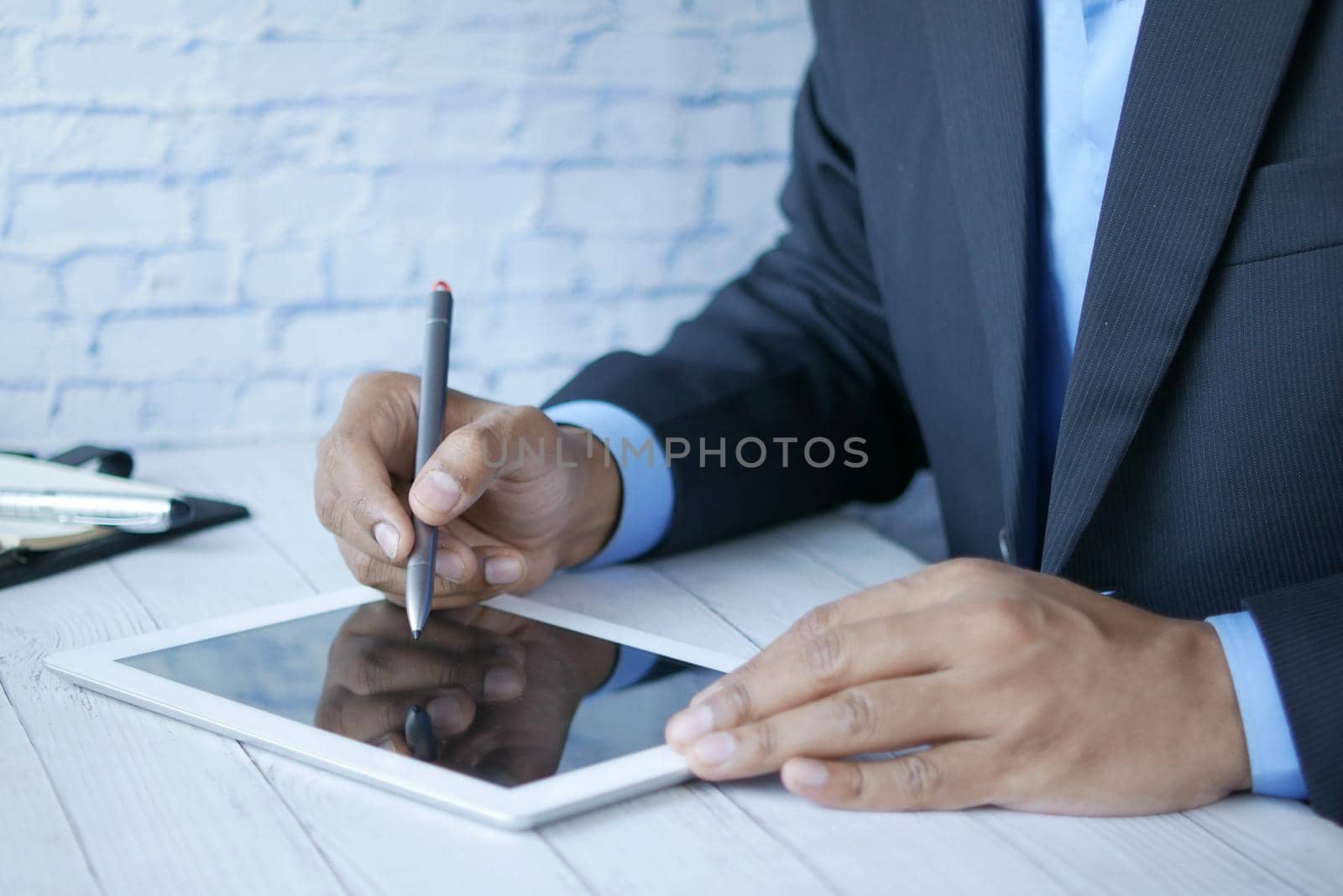 man's hand working on digital tablet at office desk