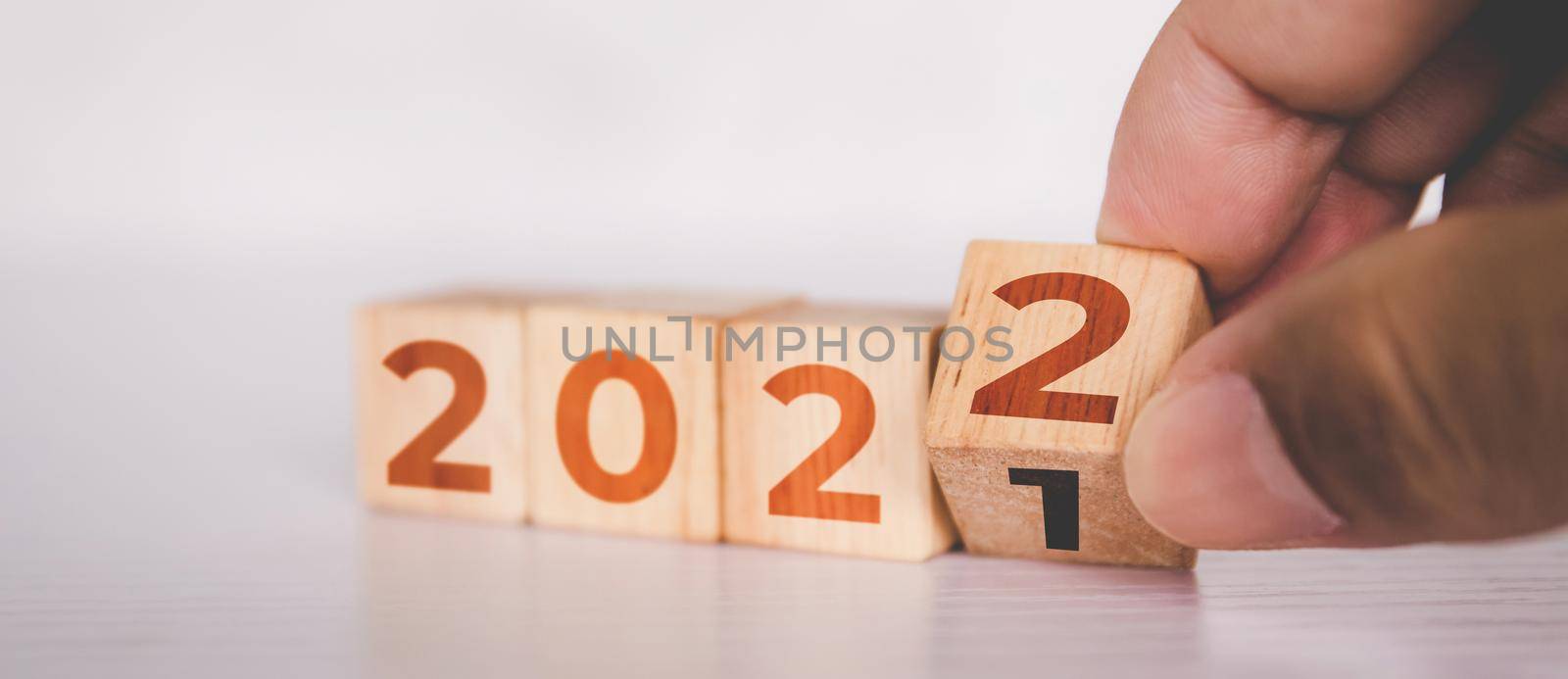 Hands flipping cube wooden block with text year 2022, beginning and trend, calendar and time, determination target and planning for achievement, motivation and aspirations, business concepts. by nnudoo