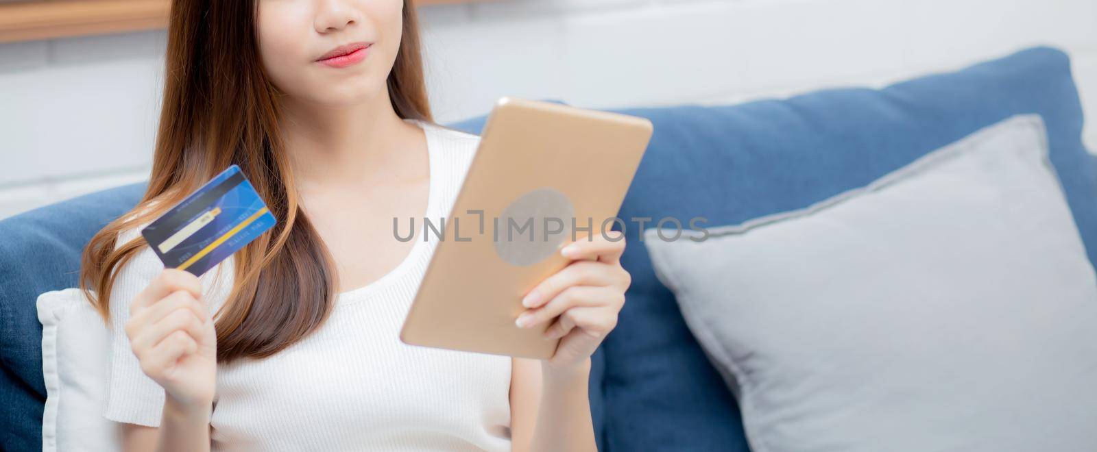 Young asian woman smiling holding credit card shopping online with tablet computer buying and payment, girl using debit card purchase or transaction of finance, lifestyle and e-commerce concept.