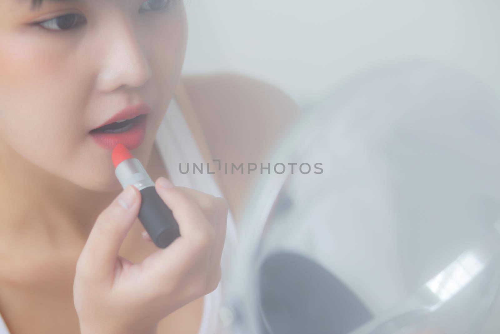 Beautiful young asian woman applying lipstick red on mouth, beauty girl looking facial at mirror for makeup cosmetic with lips elegance, make up with sexy of female, skin care and health concept. by nnudoo