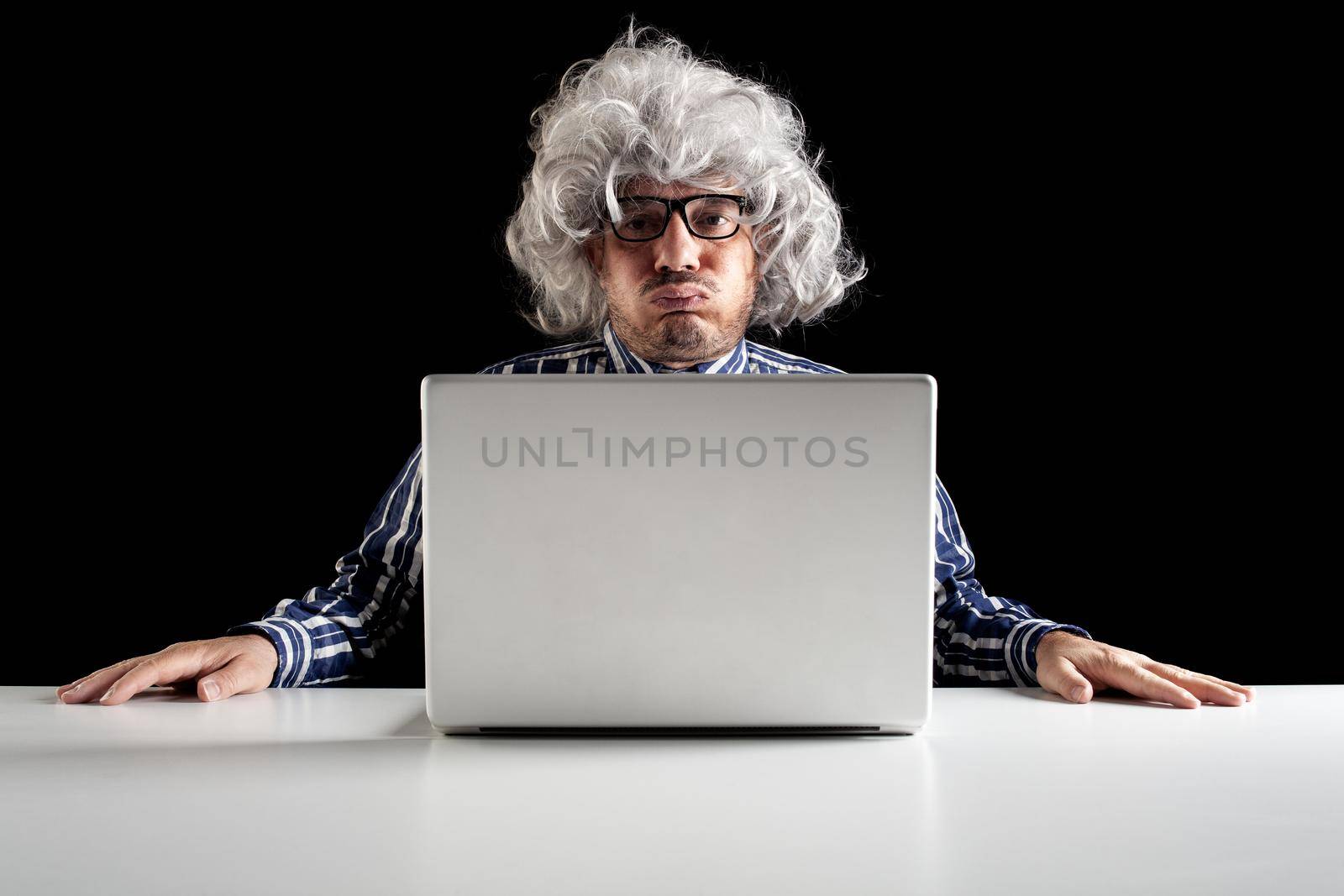 An old man boomer sitting on the desk snorting while using a computer notebook on black background