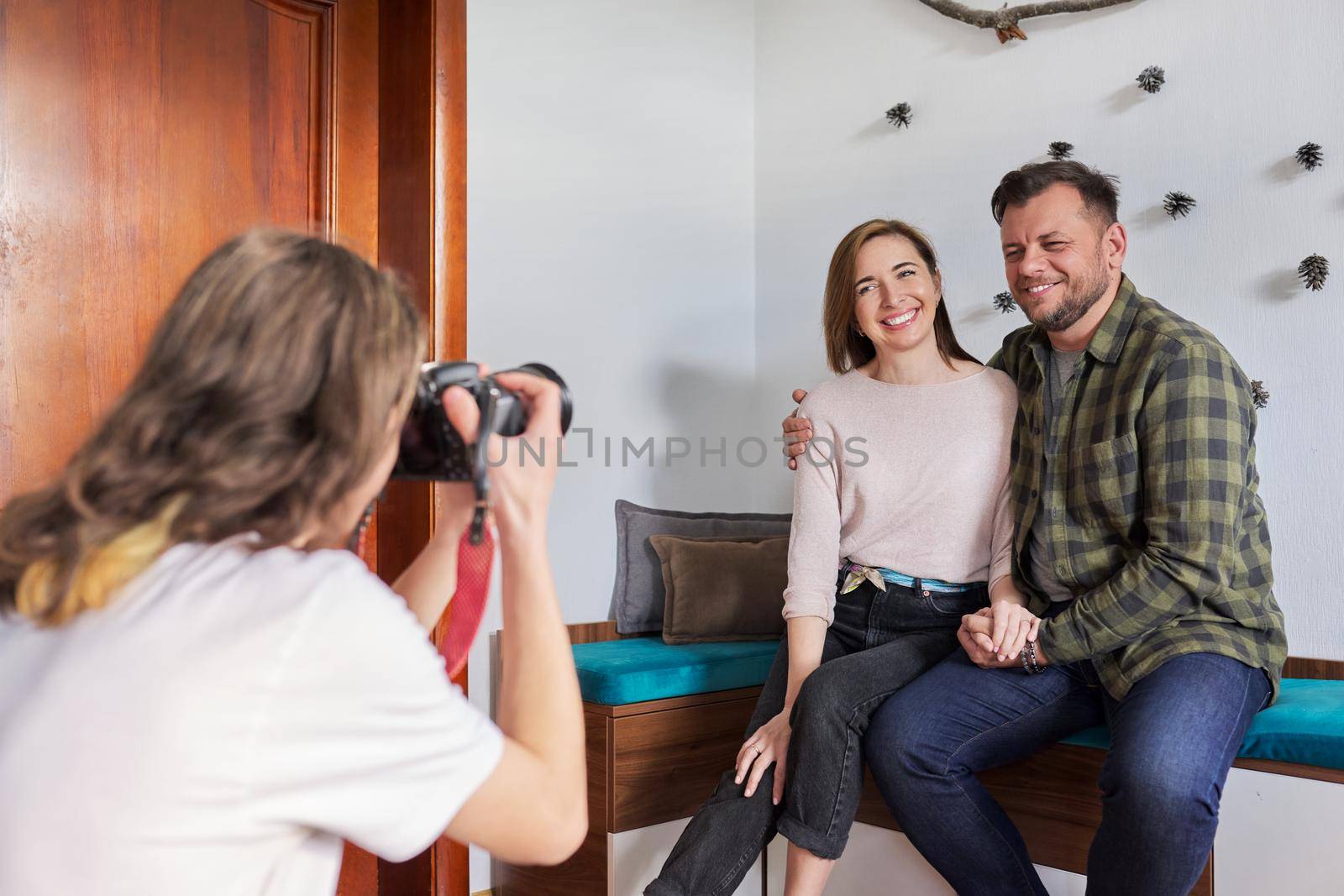 Family holiday date, happy middle-aged couple embracing posing looking into photocamera. Teenage son taking pictures of romantic parents at home, Valentine's Day