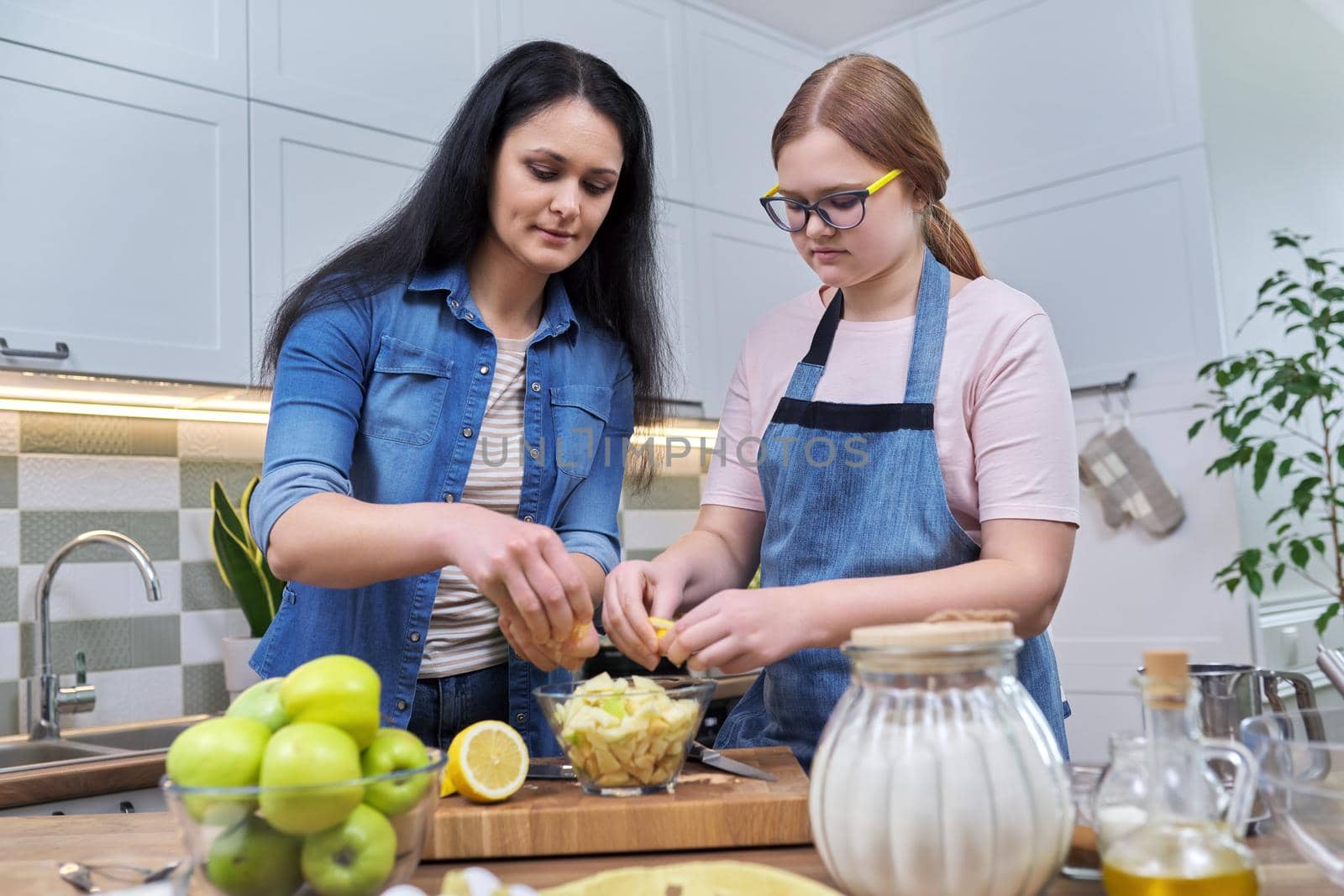 Mom and teenage daughter preparing apple pie together by VH-studio