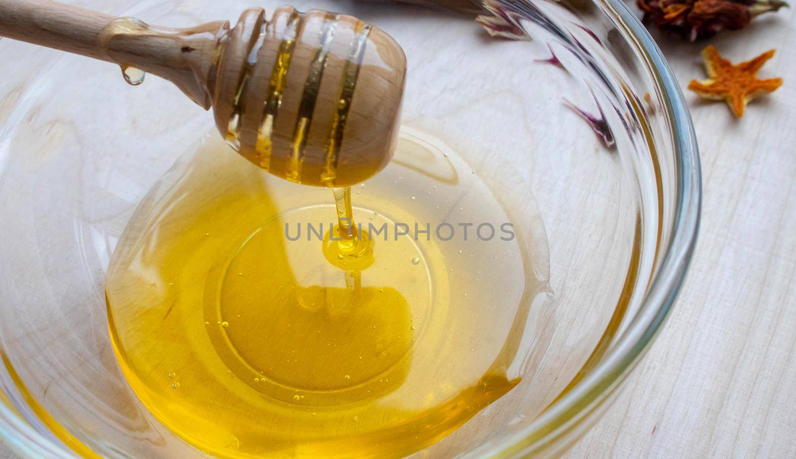 Honey dipper on the bee honeycomb background. Honey tidbit in glass jar and honeycombs wax.