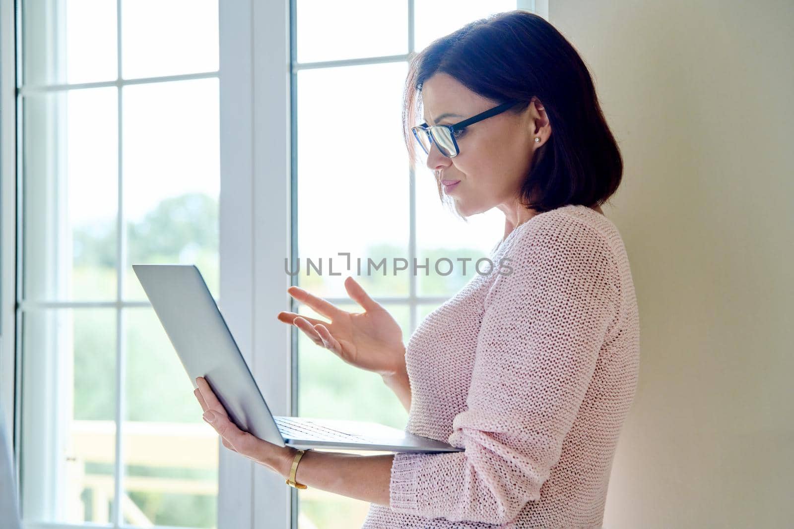 Video call, teleconference, online meeting, communication. Middle aged confident businesswoman, therapist, counselor, teacher, mentor with laptop, looking at screen talking consulting working remotely