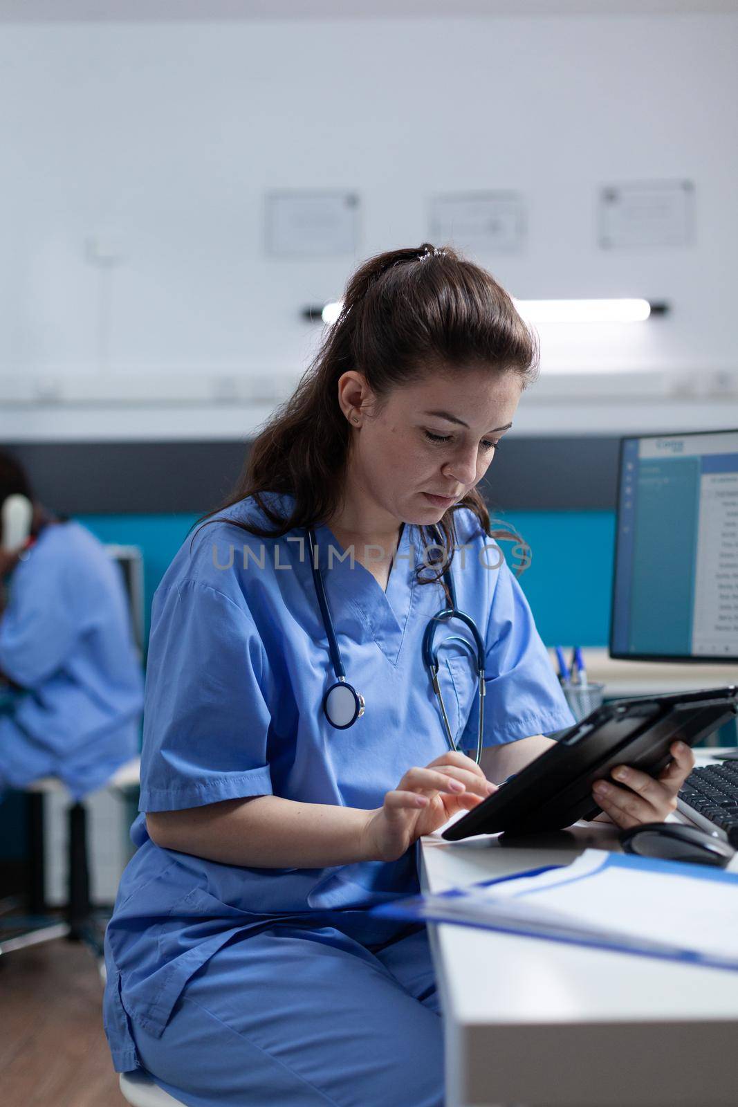 Pharmacist nurse looking at tablet computer analyzing sickness expertise working at healthcare treatment in hospital office. pediatrician asisstance checking pharmaceutical medication sitting at desk