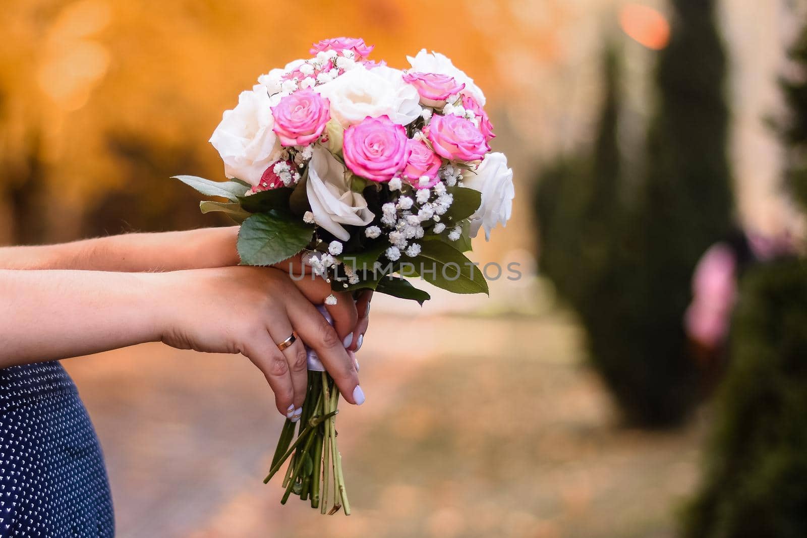 wedding bouquet of roses in the hands of the bride embracing the groom. close-up.